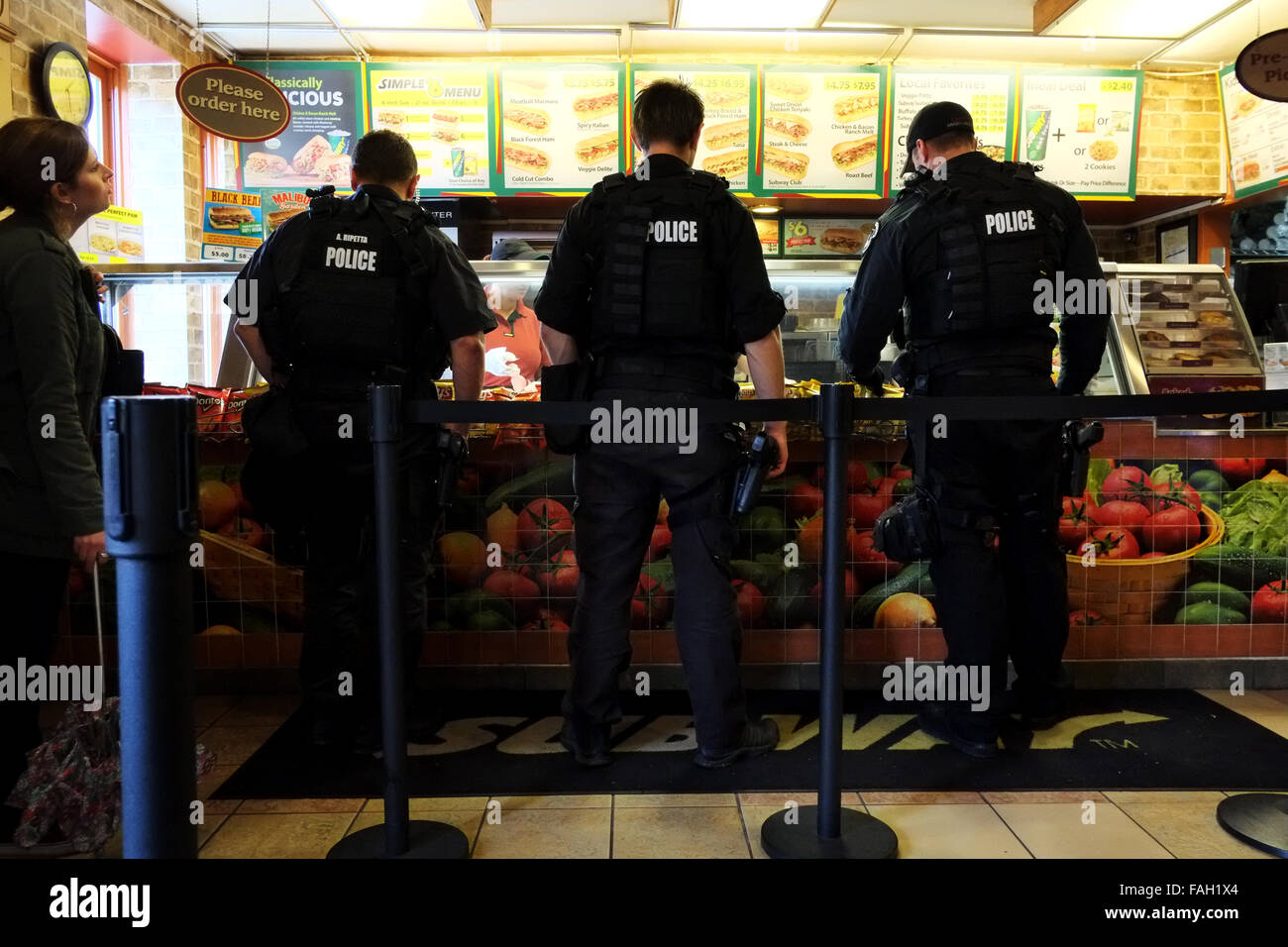 Un gruppo di poliziotti in uniforme ordinare il cibo in una metropolitana fast food a Washington DC. Essi sono tutti armati e facendo una breve pausa da loro Foto Stock