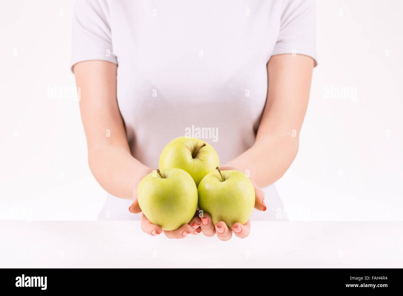 Donna dimostrando tre mele verdi. Foto Stock
