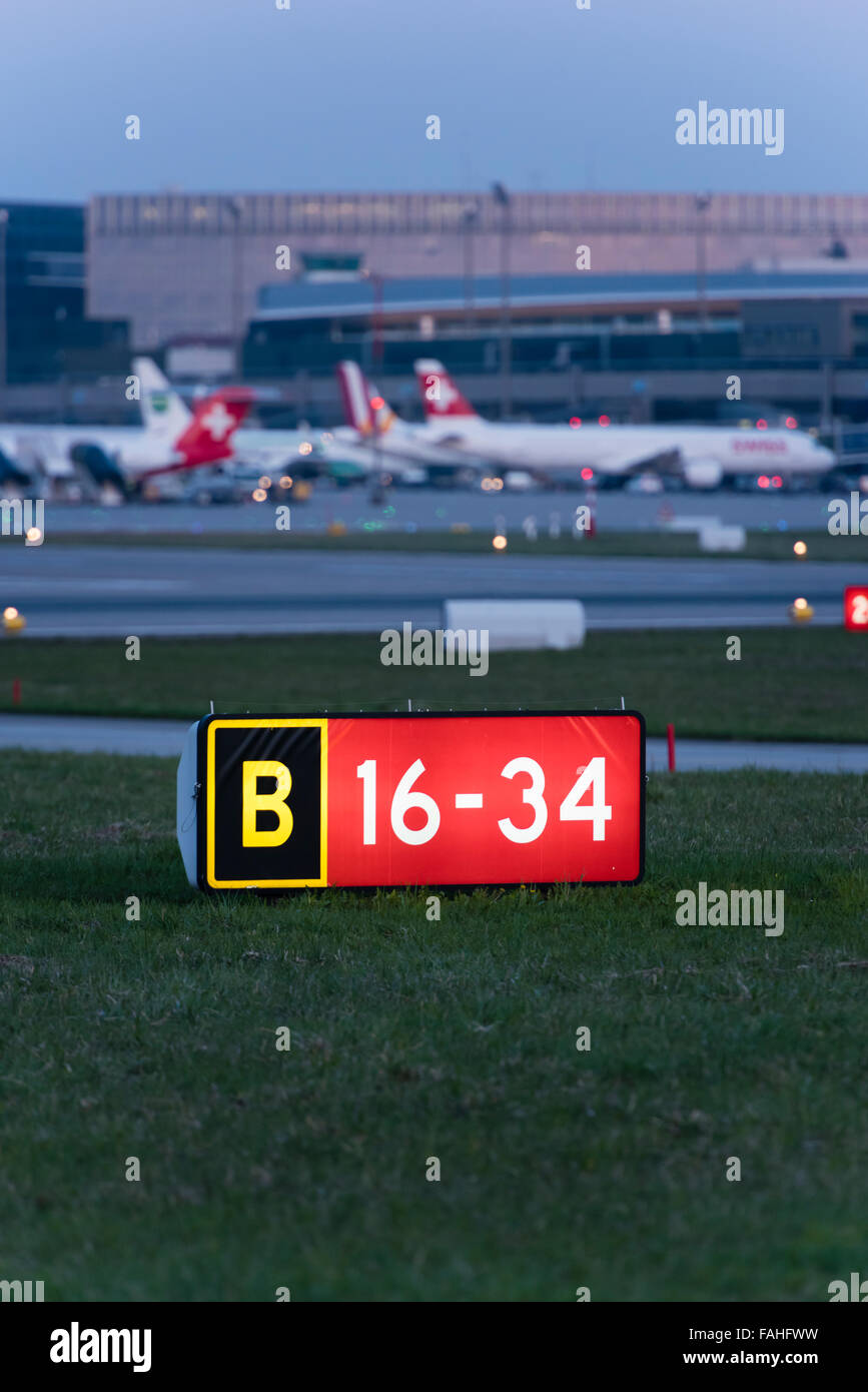 Pista illuminata e segnalazione di occupato di traffico di massa nel crepuscolo della sera all'aeroporto internazionale di Zurigo. Foto Stock