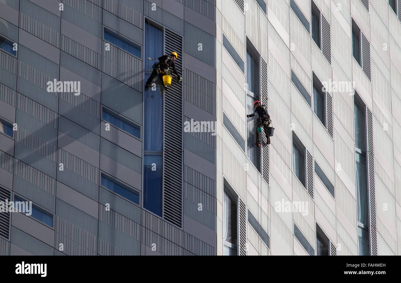 La discesa in corda doppia detergenti per finestre in un duro lavoro su un edificio in East End di Londra REGNO UNITO Foto Stock