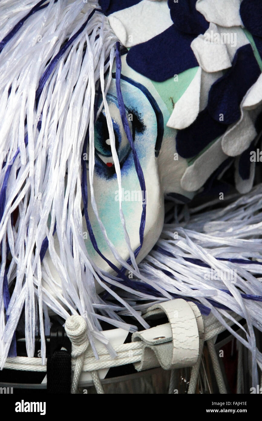 Un unico Basilea maschera di Carnevale mostra di dipinti di bianco e blu clown faccia con i capelli lunghi e hat recante sulla parte superiore di un tamburo rullante Foto Stock