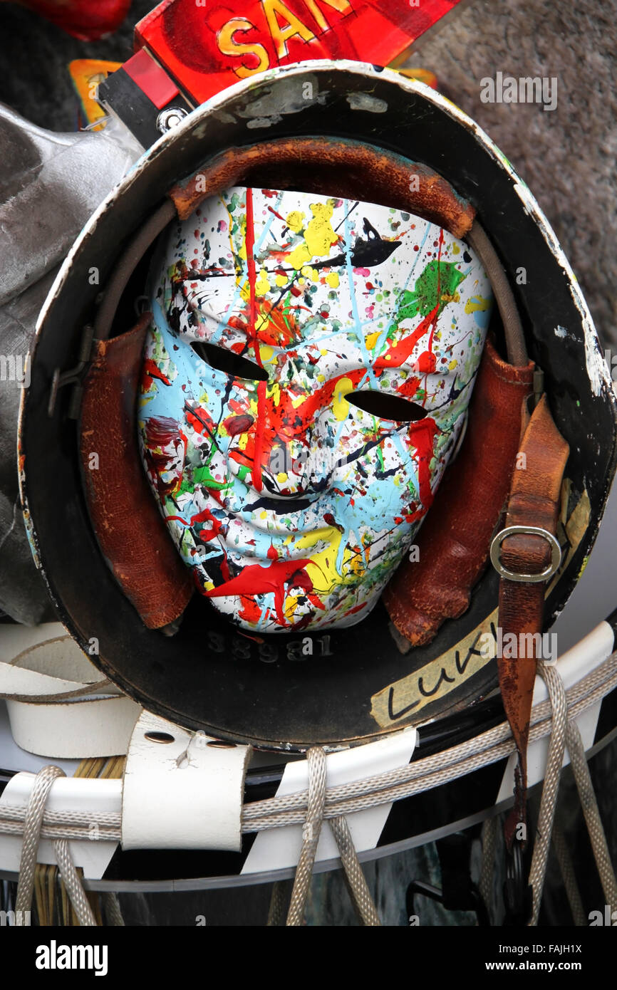 Un unico Carnevale di Basilea maschera che mostra un colorato e luminoso volto sorridente in un vecchio esercito casco recante sulla parte superiore di un tamburo rullante Foto Stock