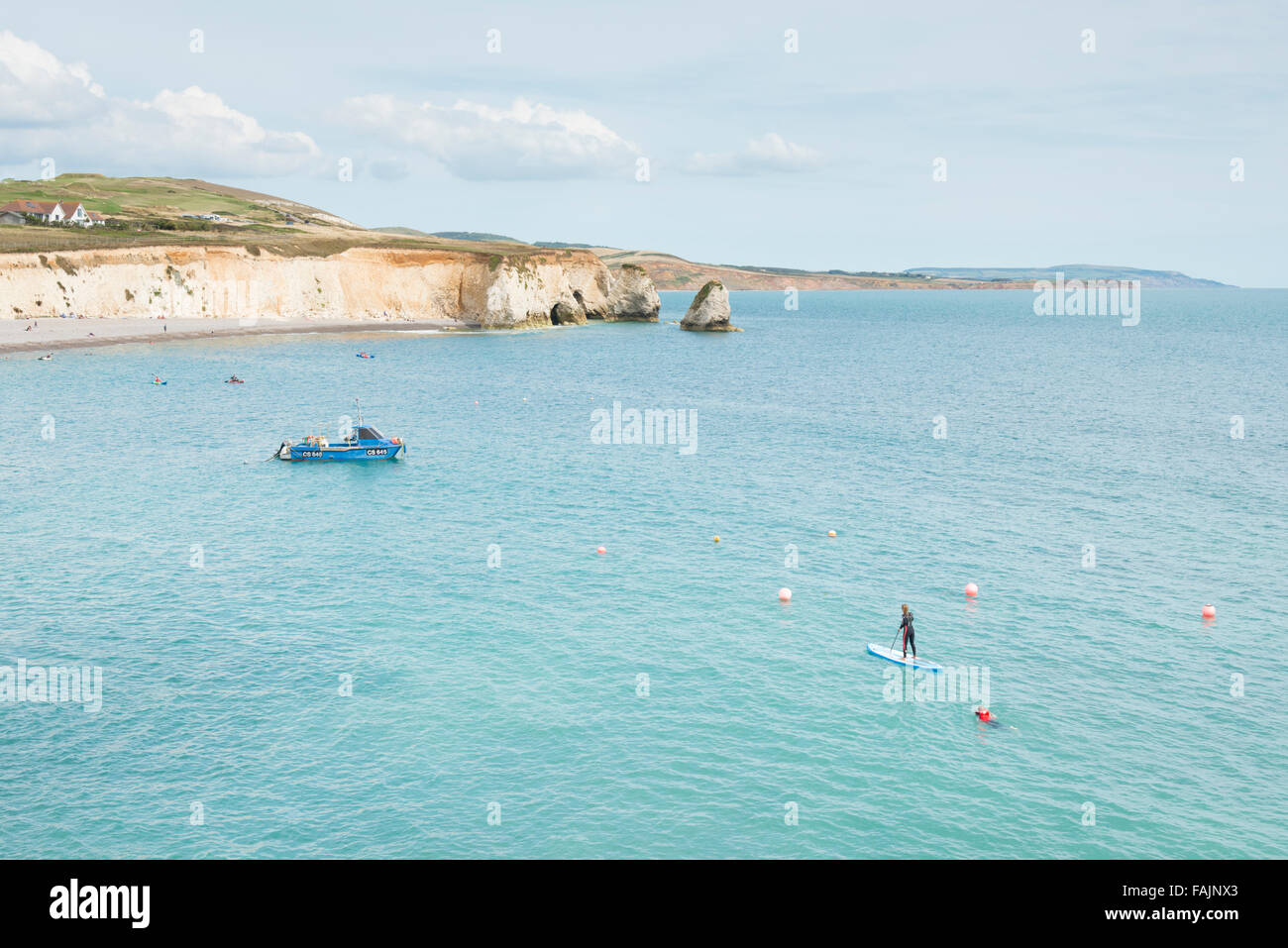 La spiaggia e le scogliere a Freshwater Bay Isle of Wight UK con persone in acqua paddleboarding Foto Stock