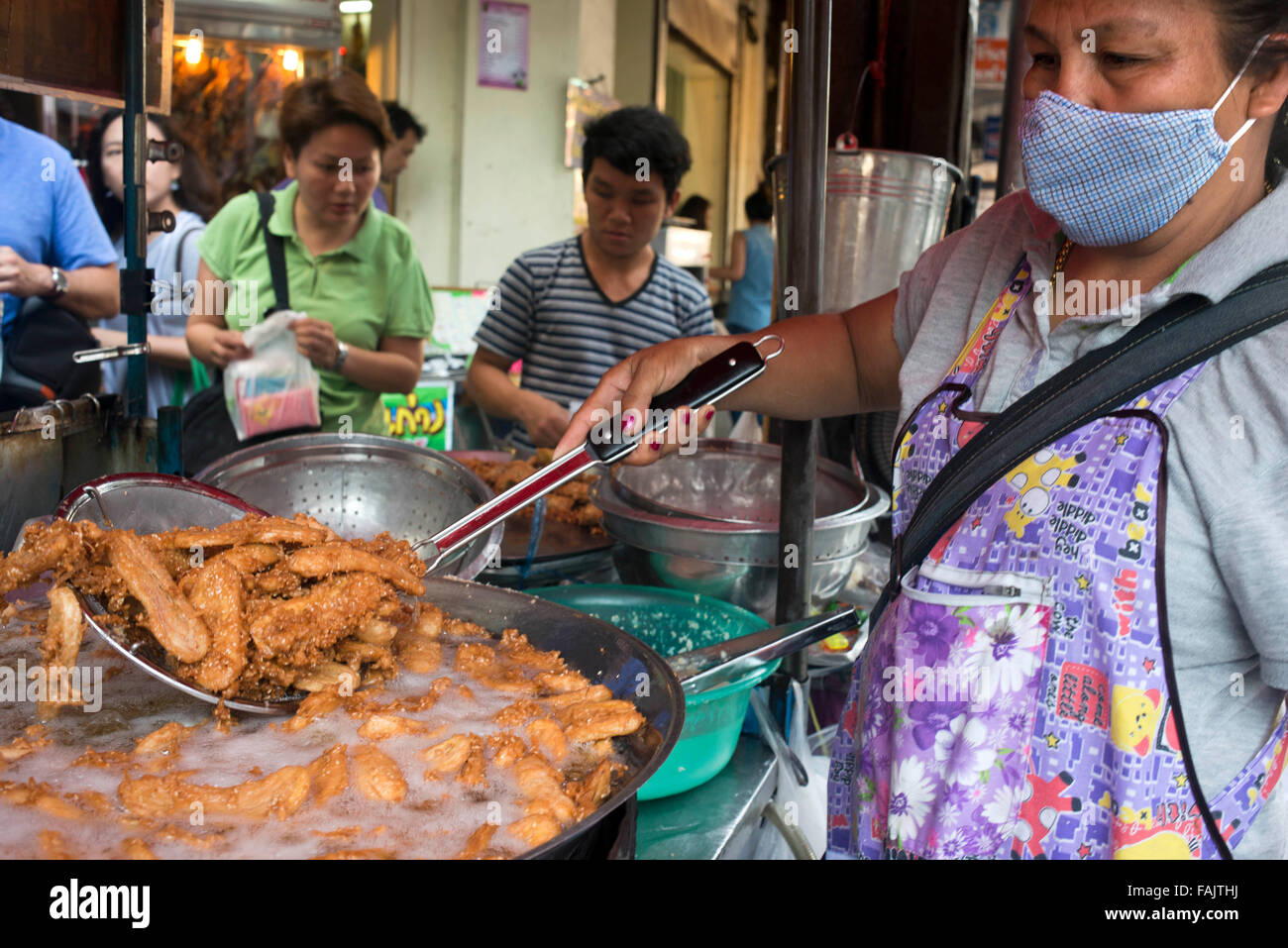 Je Noi, banane fritte stallo, kluay keak in Thanon Charoen Krung, Bangkok, Thailandia. Banane fritte carrello, angolo di Charoen Krung e Si Wiang. Aperto giornalmente da metà mattina fino al tardo pomeriggio. È possibile vedere come le banane fresche, patate dolci e radici di taro sono febbrilmente sbucciato e tagliato a fette e fritto per tenere il passo con le esigenze. Non puoi perderti questo cibo carrello situato proprio in corrispondenza della zona di spigolo di Charoen Krung e Si Wiang. Linea di persone fino al momento in cui la prima partita di pastella-banane fritte colpisce l'olio fino a che il tutto non si esaurisce. Foto Stock