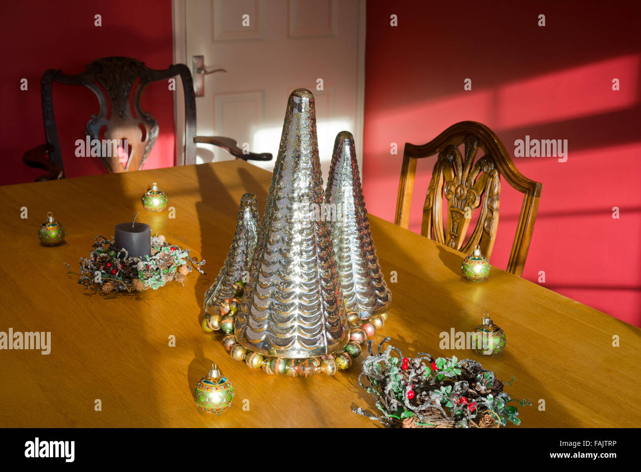 Le decorazioni di Natale. Albero di natale di argento a forma di decorazioni di vetro su un piano di un tavolo, con baubles e candela. Foto Stock