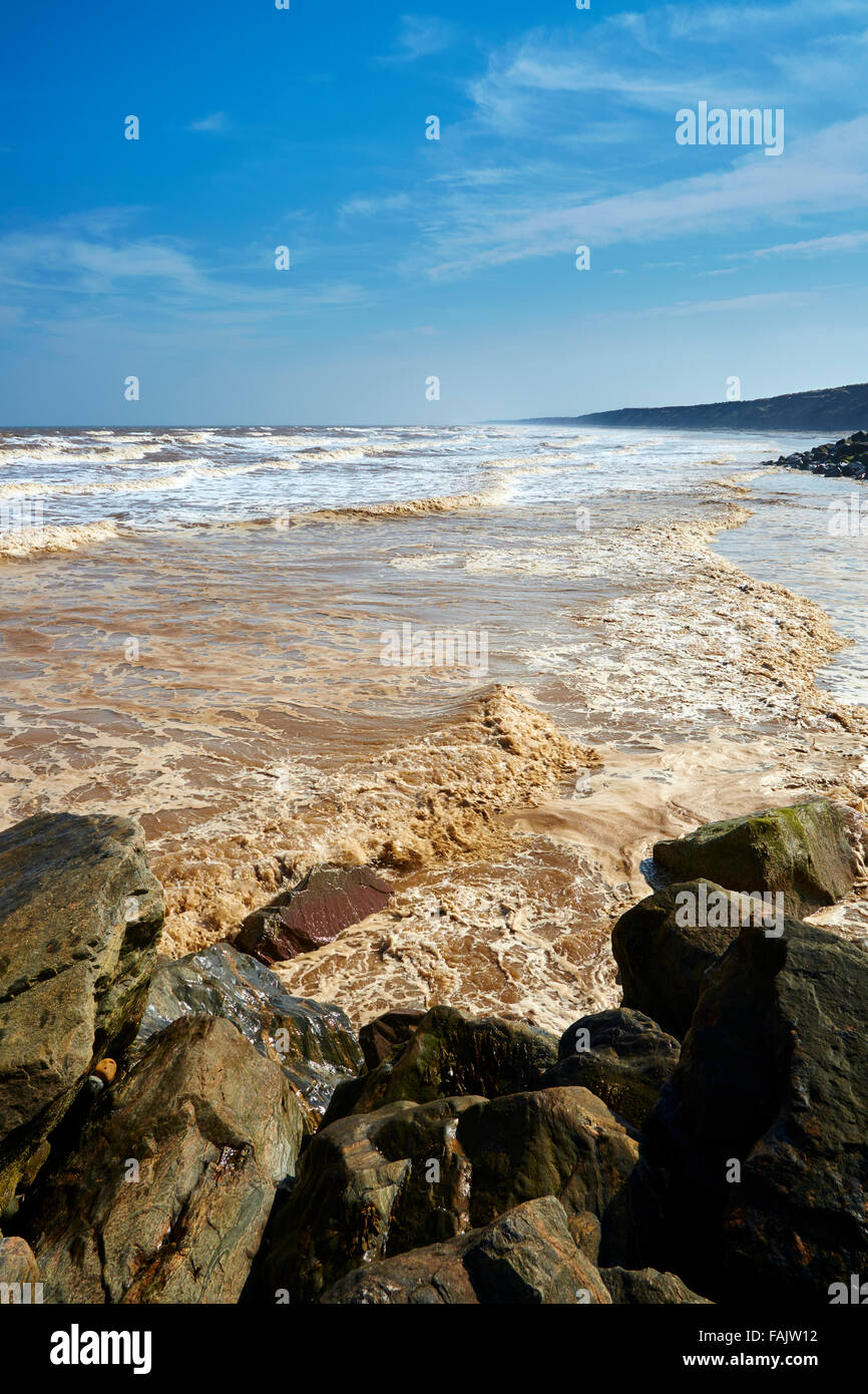 Un po' di mare mosso si rompe in piccole onde contro le rocce sulla spiaggia Mappleton Foto Stock