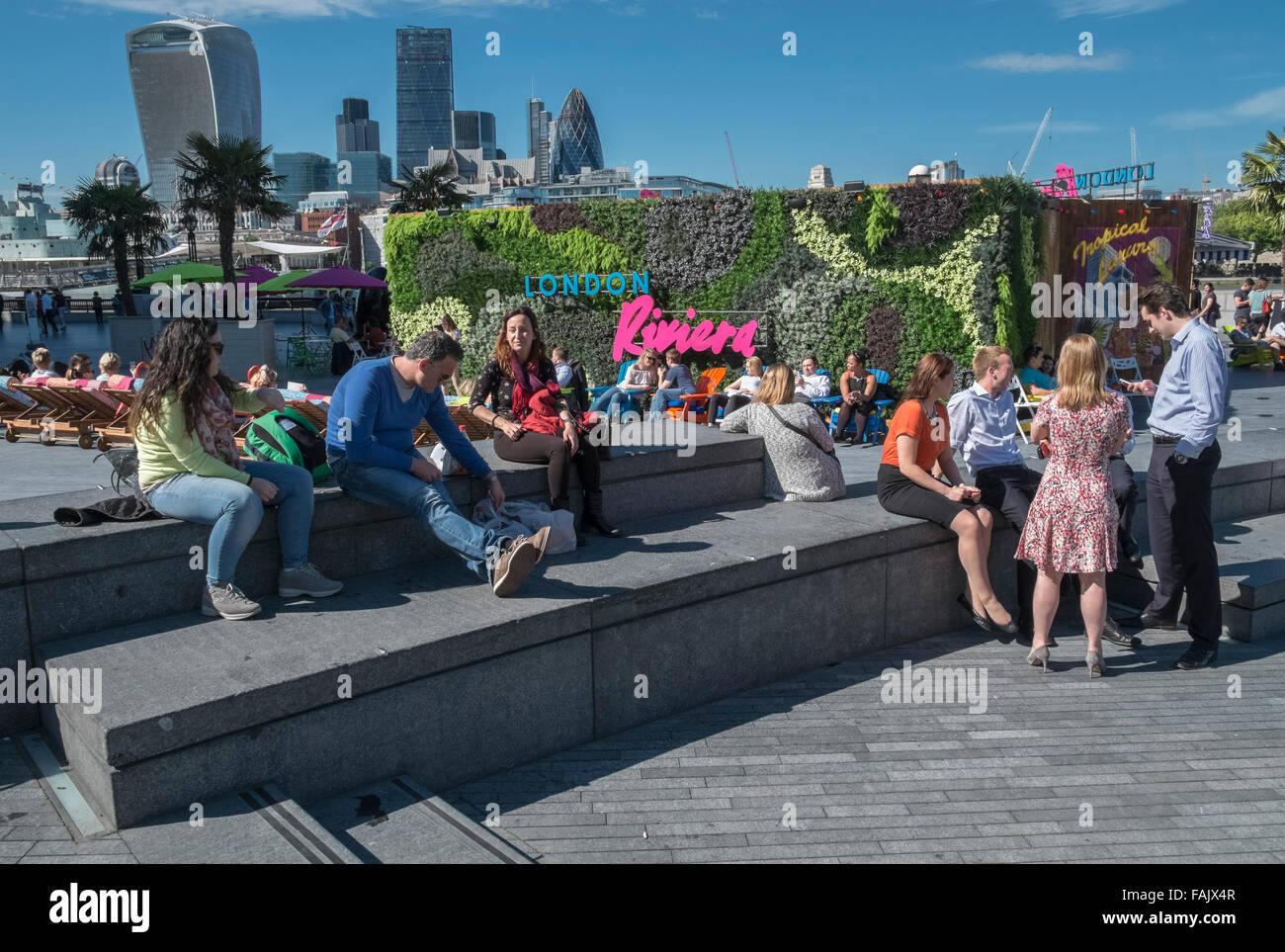 Persone rilassarsi e socializzare in estate il sole a Londra Riviera pop up ristorante, con lo skyline di Londra in background, REGNO UNITO Foto Stock