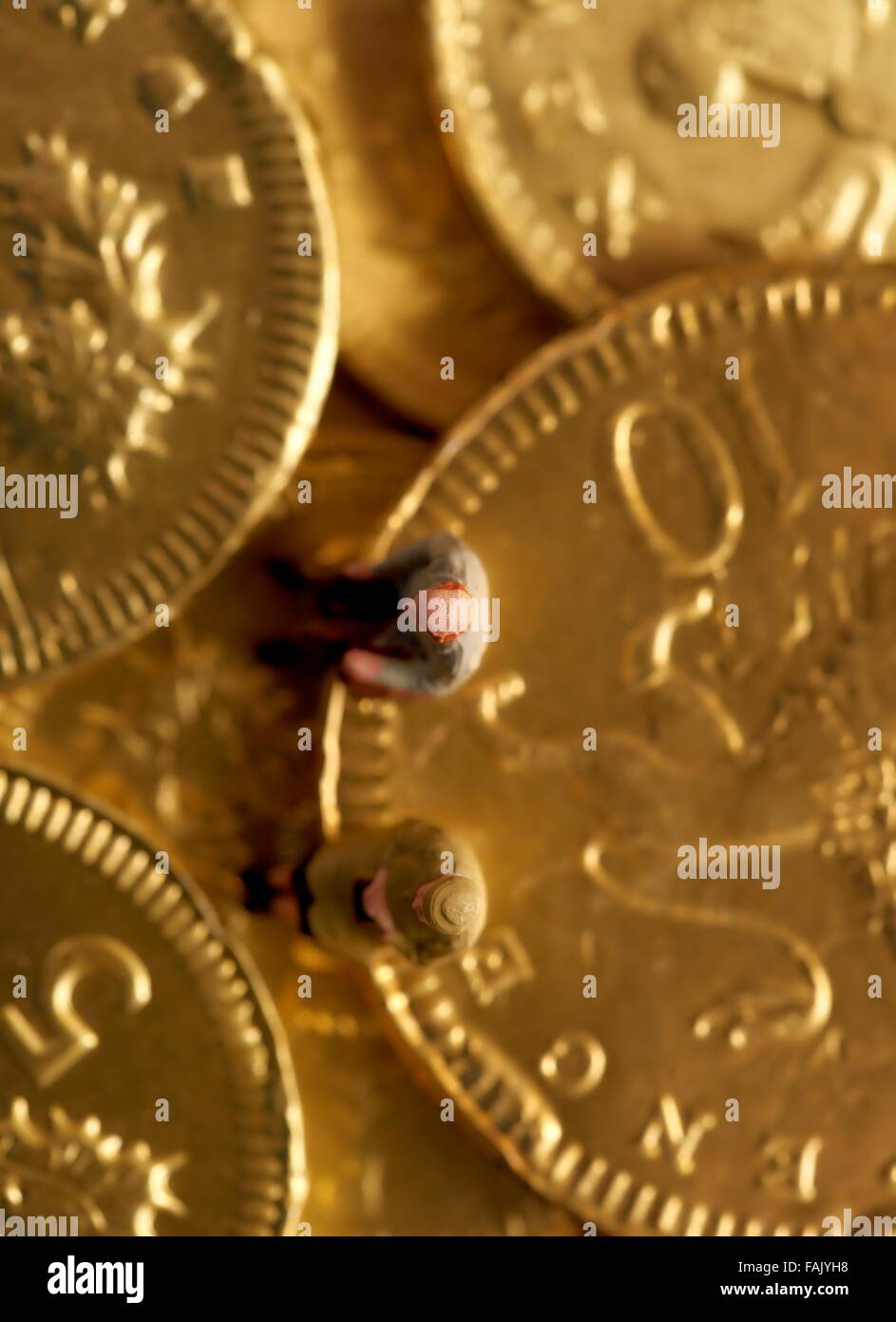 Miniatura gente seduta sul cioccolato monete di denaro Foto Stock