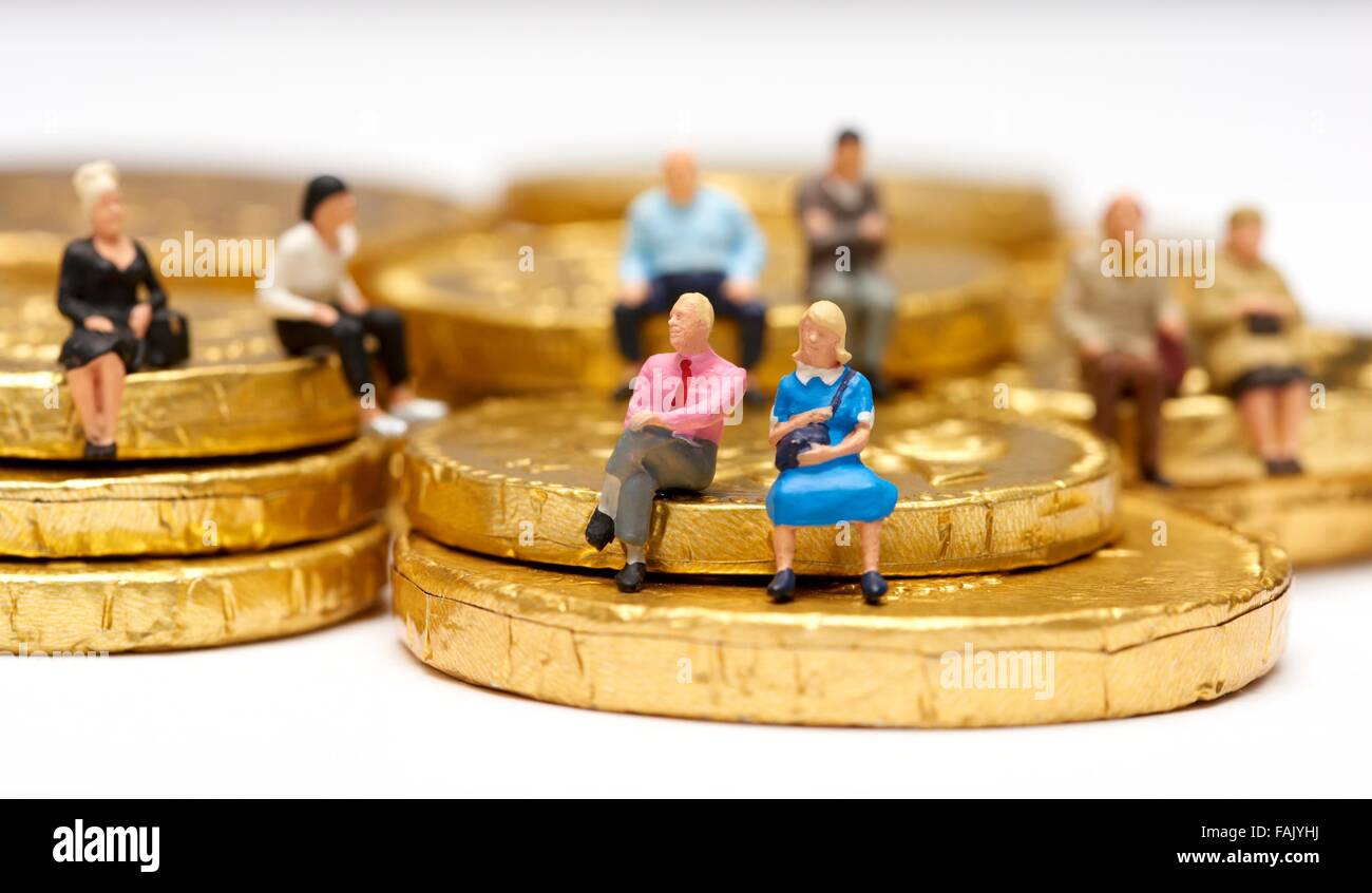 Miniatura gente seduta sul cioccolato monete di denaro Foto Stock