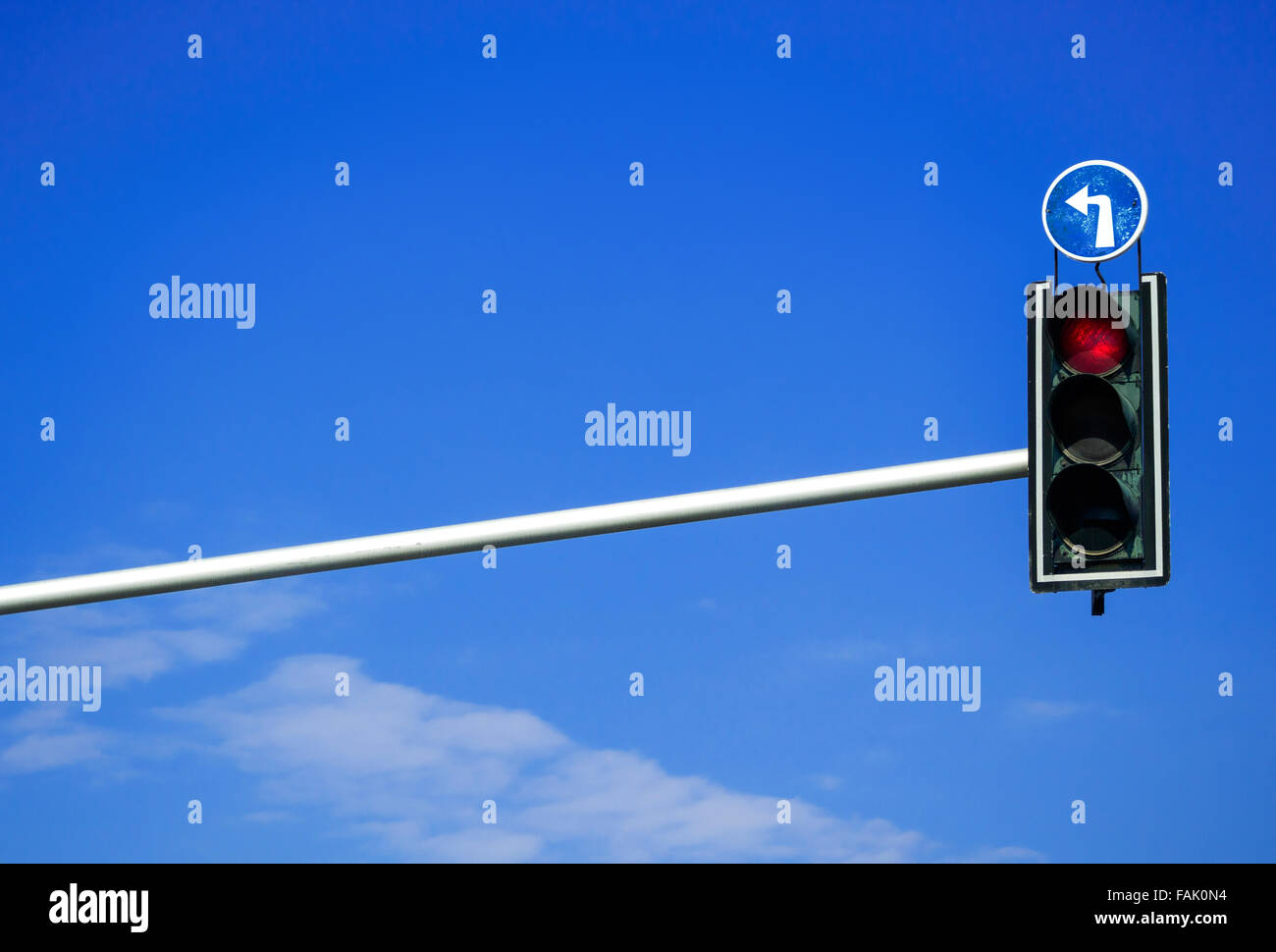 Luce rossa in una curva a sinistra semaforo con cielo blu sullo sfondo Foto Stock