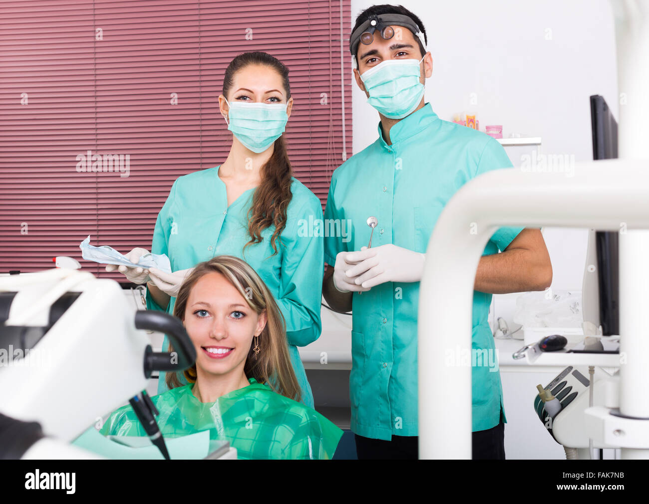 Bionda paziente femmina e la clinica dentale equipaggio. Messa a fuoco selettiva Foto Stock