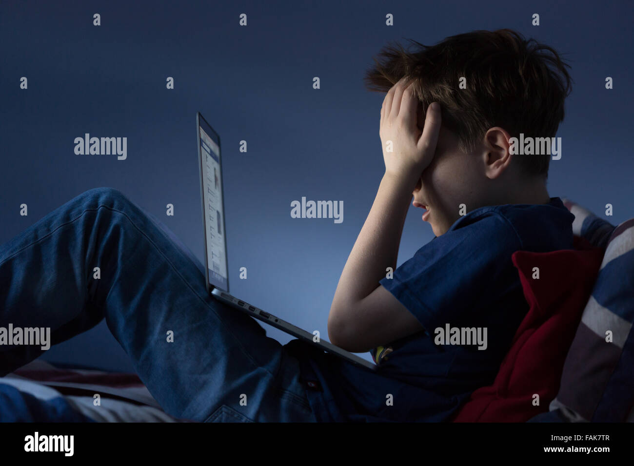 Online cyber bullismo Bullismo foto di un ragazzo sconvolto nella sua camera da letto guardando doloroso messaggi sui social media Foto Stock