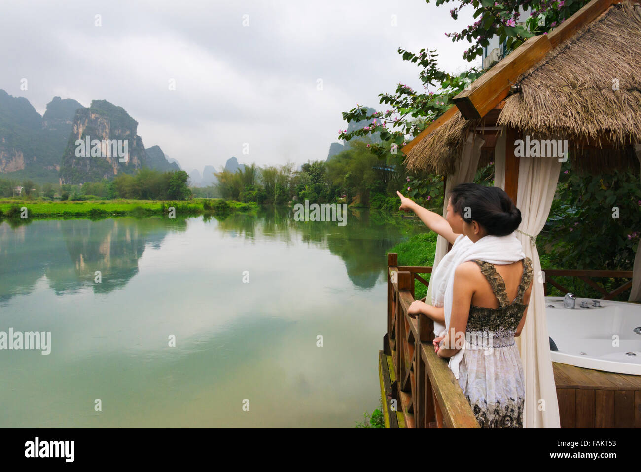 I turisti in spa balcone a guardare le colline carsiche sul fiume Mingshi, provincia di Guangxi, Cina Foto Stock