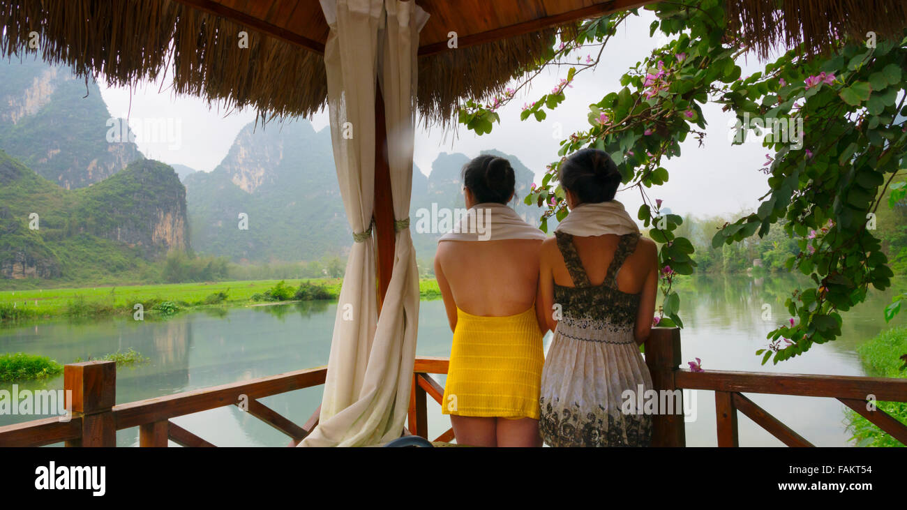 I turisti in spa balcone a guardare le colline carsiche sul fiume Mingshi, provincia di Guangxi, Cina Foto Stock