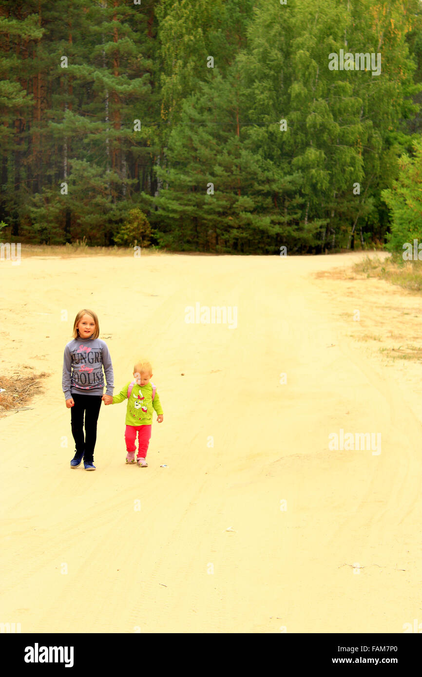 Piccole sorelle andare su una strada forestale tenendo le mani Foto Stock