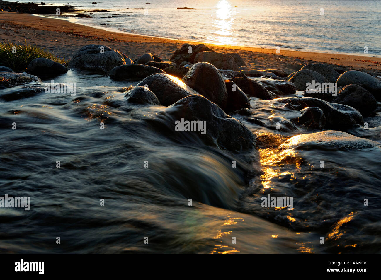 Acqua di ruscello che scorre su pietre sulla spiaggia al tramonto, Reykjanes, Westfjords, Islanda, l'Europa. Foto Stock