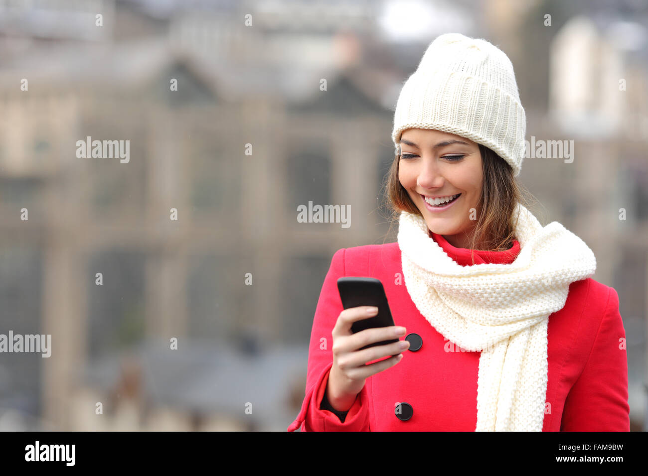 Ragazza texting in un telefono cellulare vestito calorosamente trovanella street in inverno Foto Stock