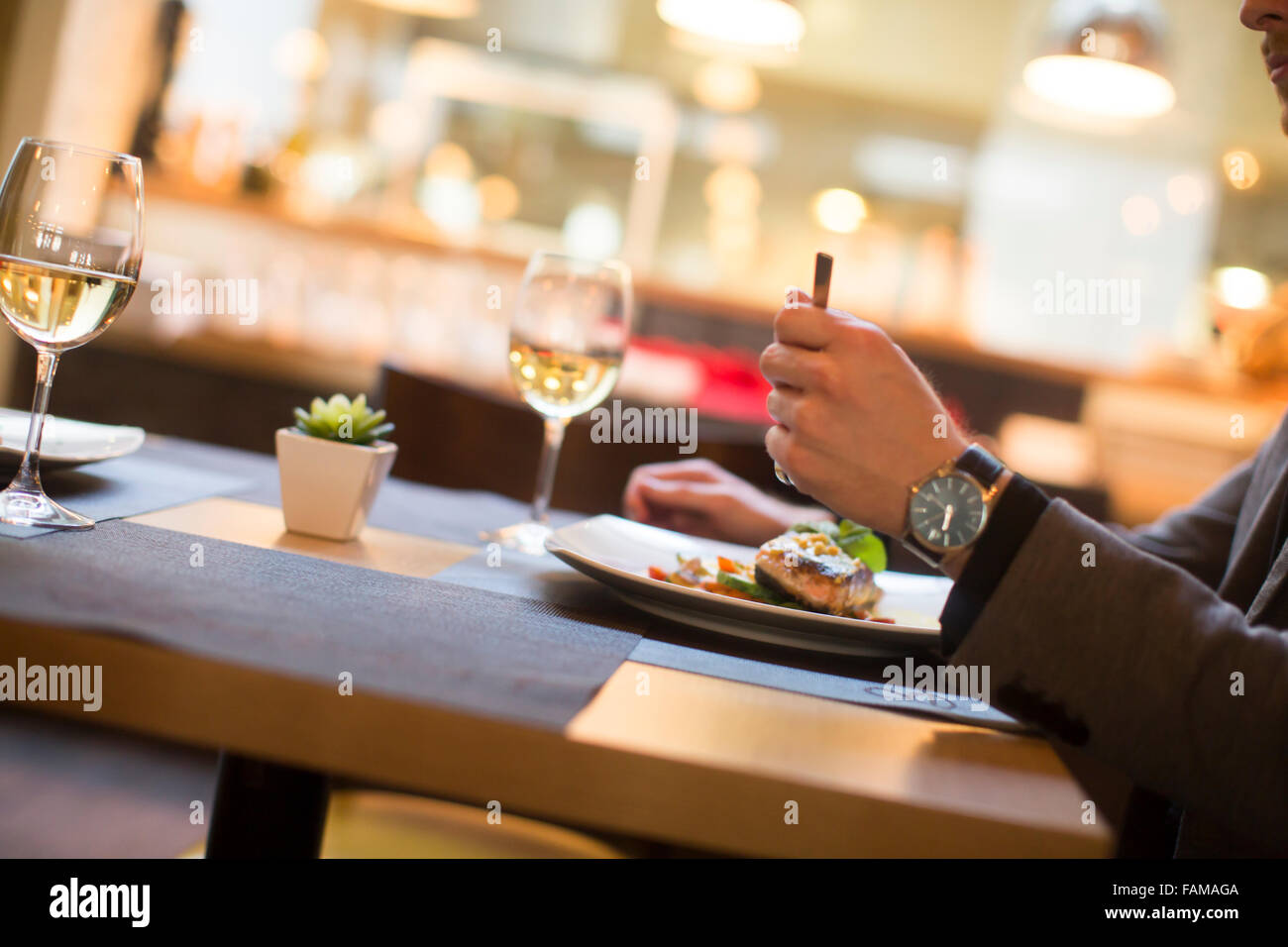 Giovane uomo mangiare salmone alla griglia con salsa di pomodoro e le erbe serviti presso il ristorante Foto Stock