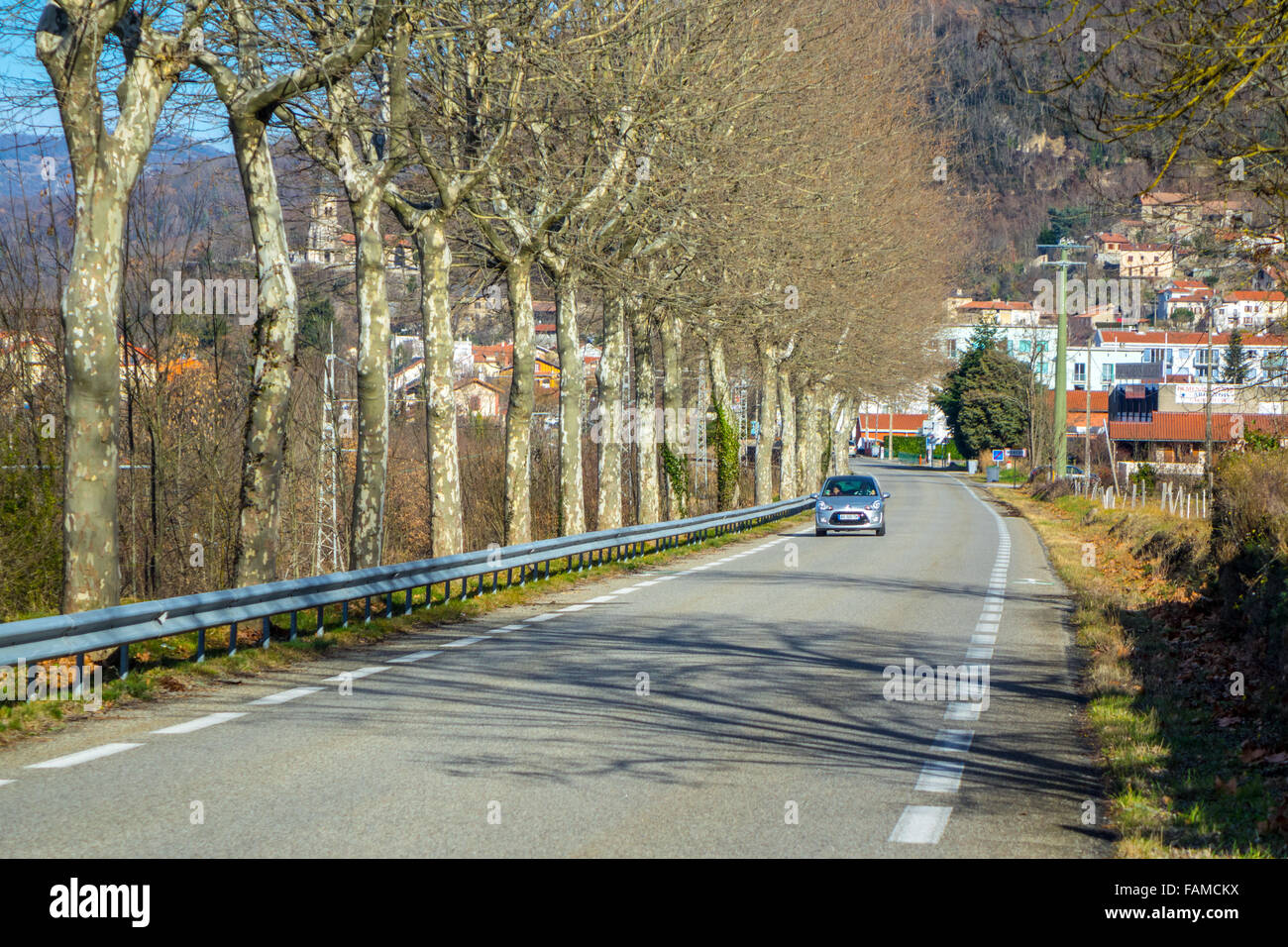 Grigio argento auto sulla strada con crash barriera rivestiti con alberi Foto Stock