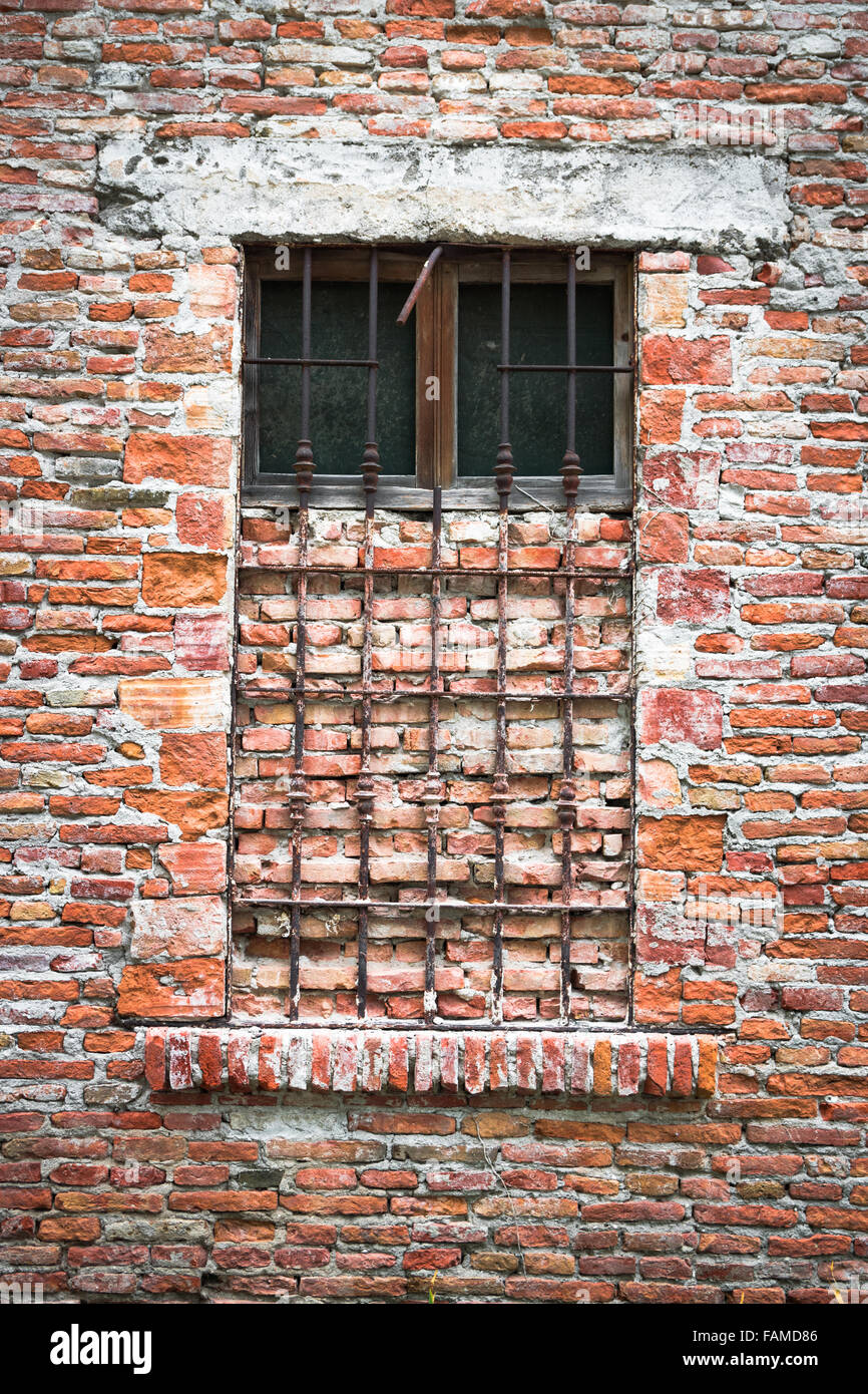 Vecchia finestra di una casa abbandonata chiusa con mattoni. Foto Stock