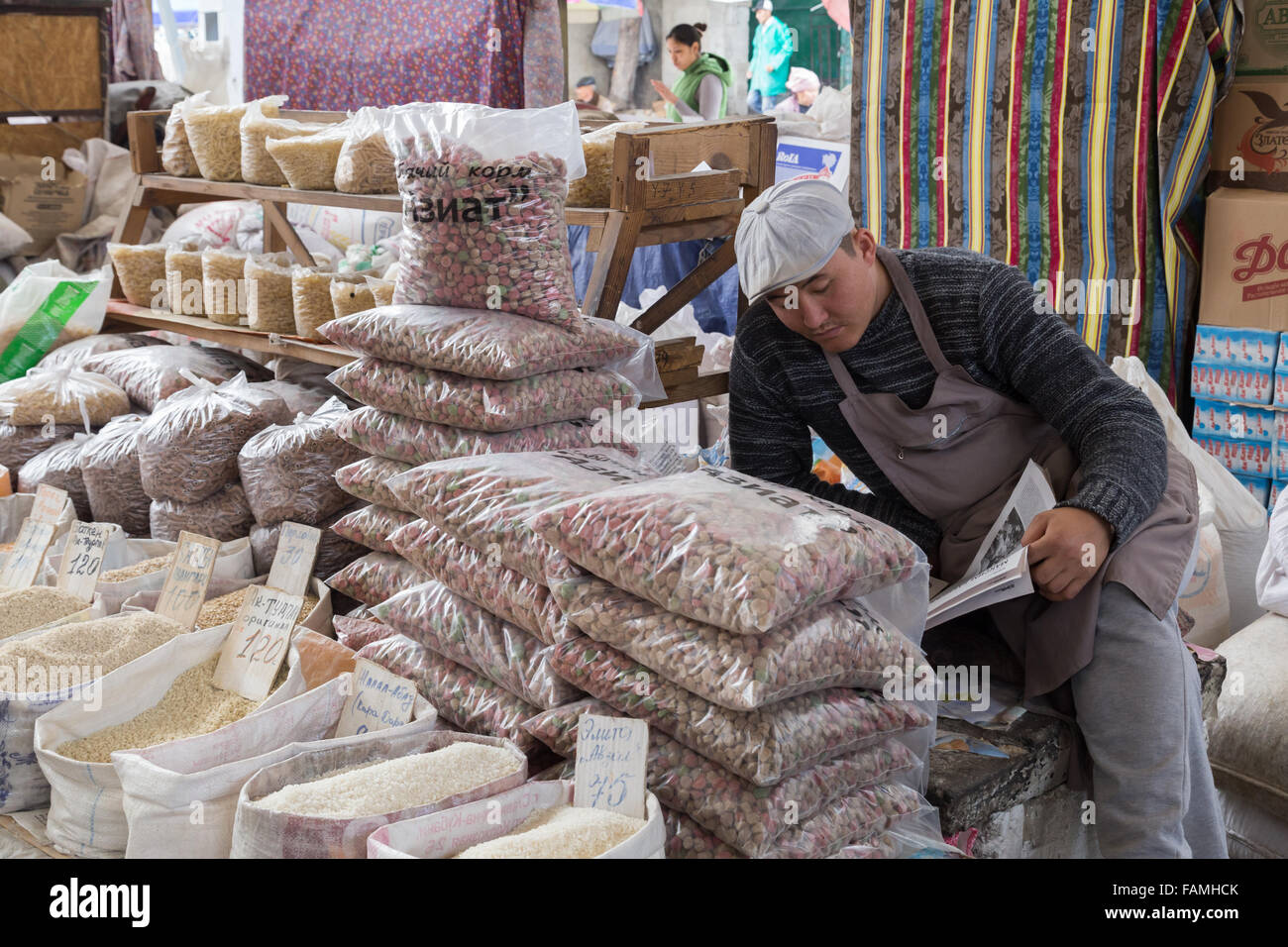 Bishkek, Kirghizistan - Ottobre 2, 2014: un venditore al bazar di ssl avente una pausa e la lettura del giornale. Foto Stock