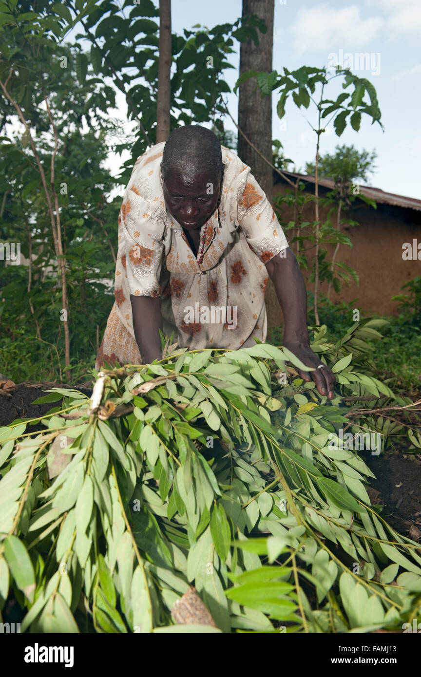 La donna prepara una una buca per il fuoco per fare carbone a vendere al mercato. Kenya. Foto Stock