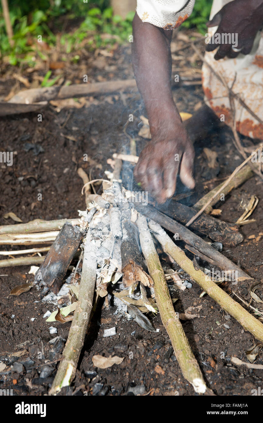 La donna prepara una una buca per il fuoco per fare carbone a vendere al mercato. Kenya. Foto Stock
