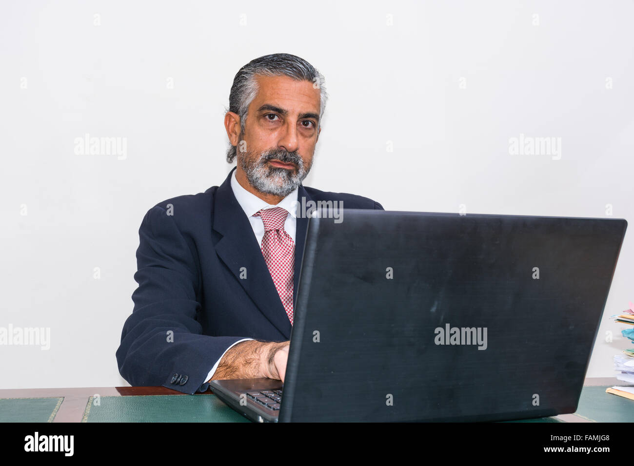 Imprenditore in un vestito e cravatta, nel suo studio. Alla scrivania, utilizzando il PC. Foto Stock