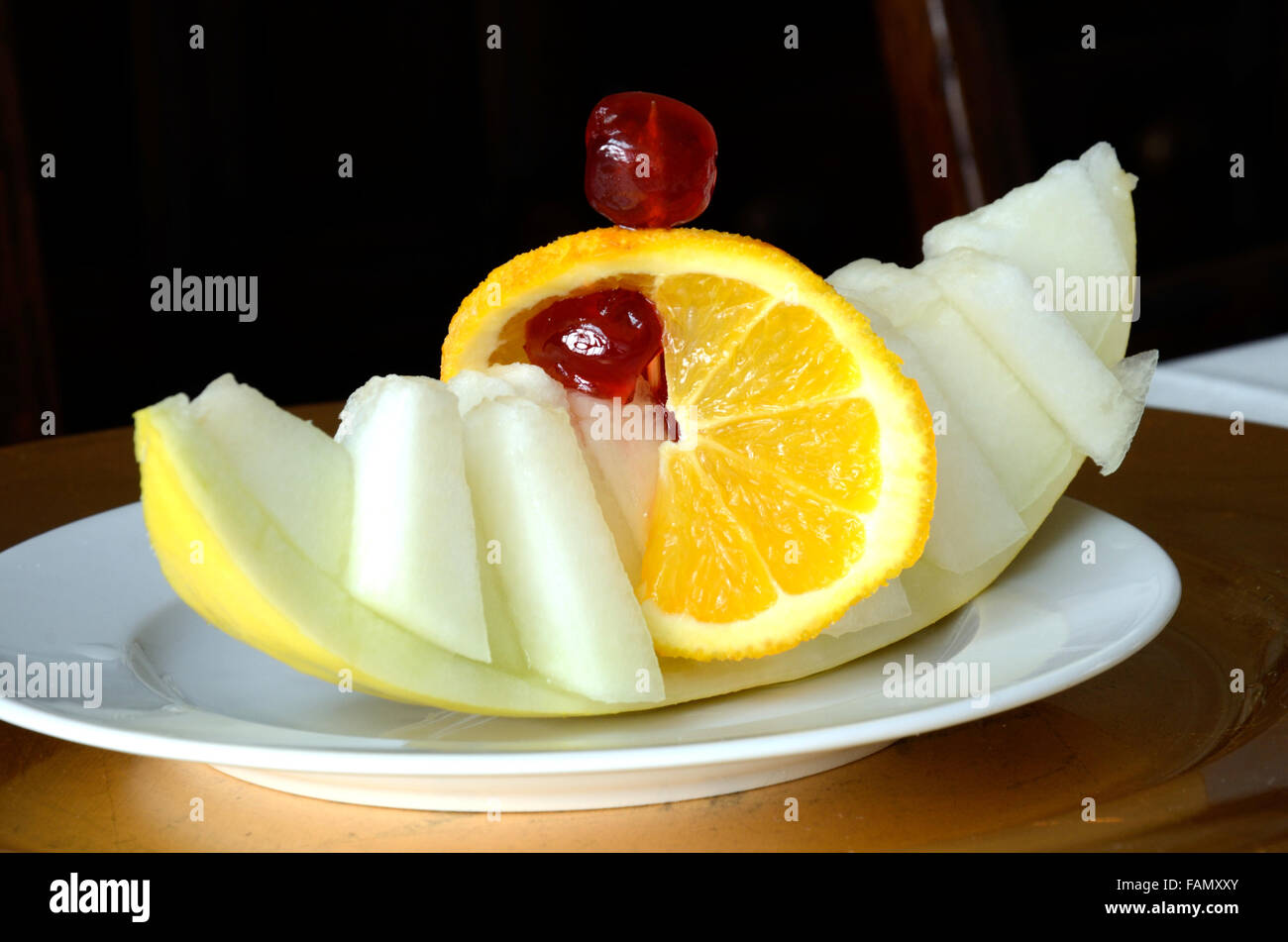 Una fetta di melone Honeydew tagliato a pezzetti e presentato come un motorino di avviamento. Esso è presentato per assomigliare ad un viking barca a vela. Foto Stock