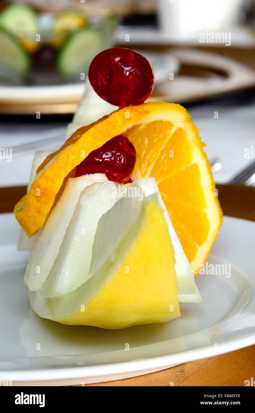 Una fetta di melone Honeydew tagliato a pezzetti e presentato come un motorino di avviamento. Esso è presentato per assomigliare ad un viking barca a vela. Foto Stock