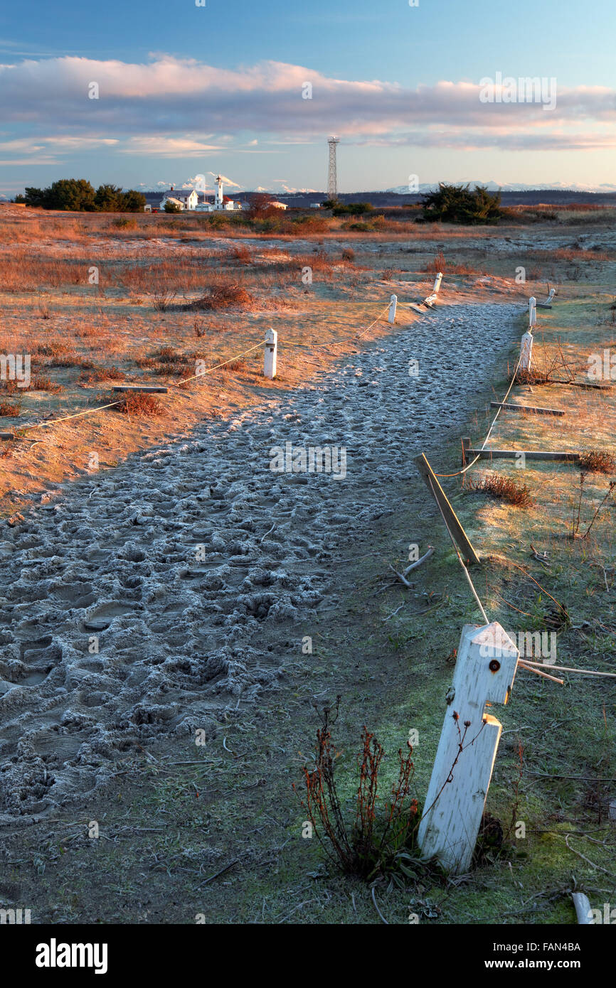 Percorso di sabbia in spiaggia al tramonto con Punto Faro di Wilson e il Monte Baker in distanza, Fort Worden parco statale, Port Townsend, Foto Stock