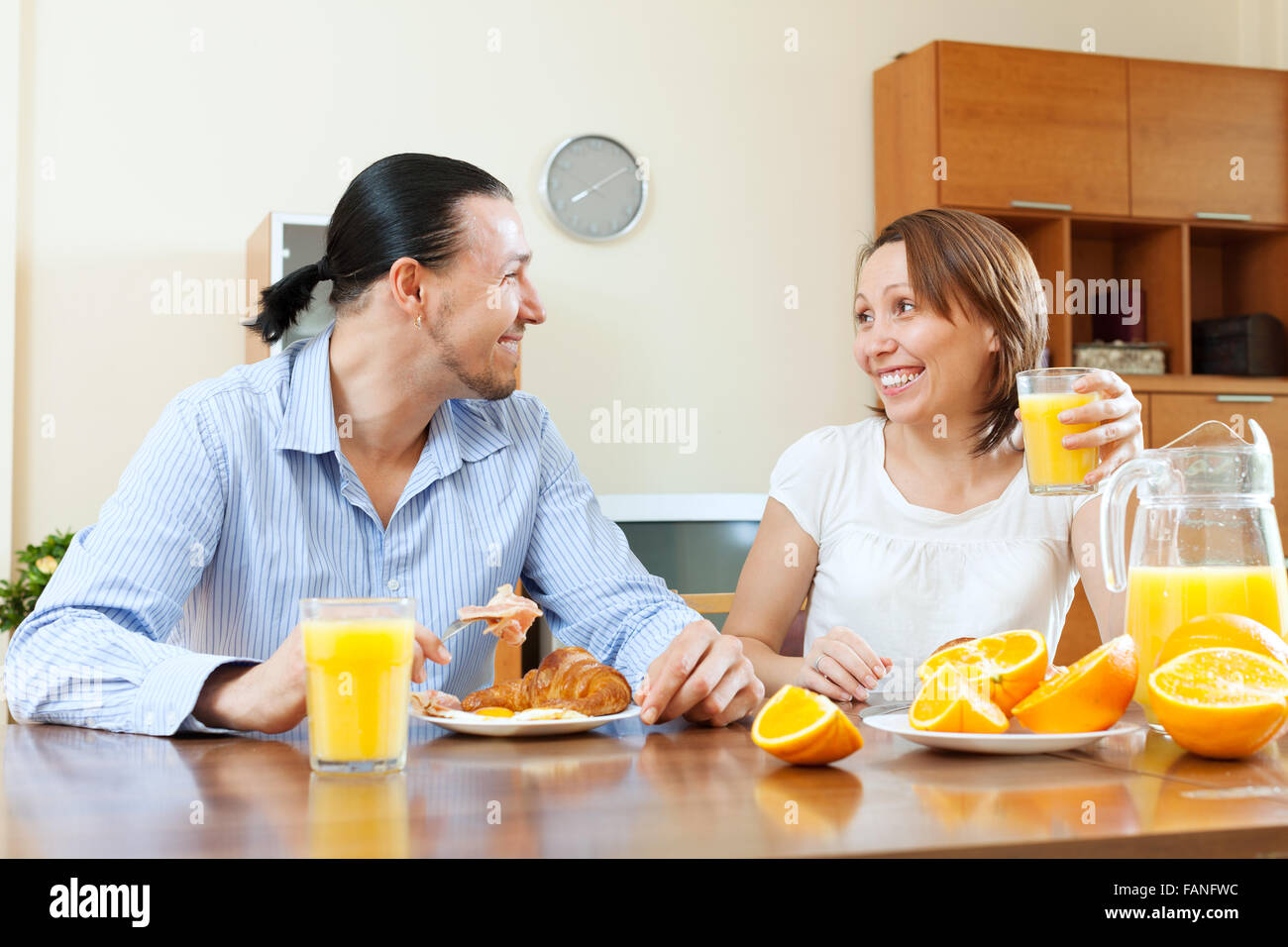 Coppia felice di fare colazione con uova strapazzate e succo di arance in mattina insieme Foto Stock