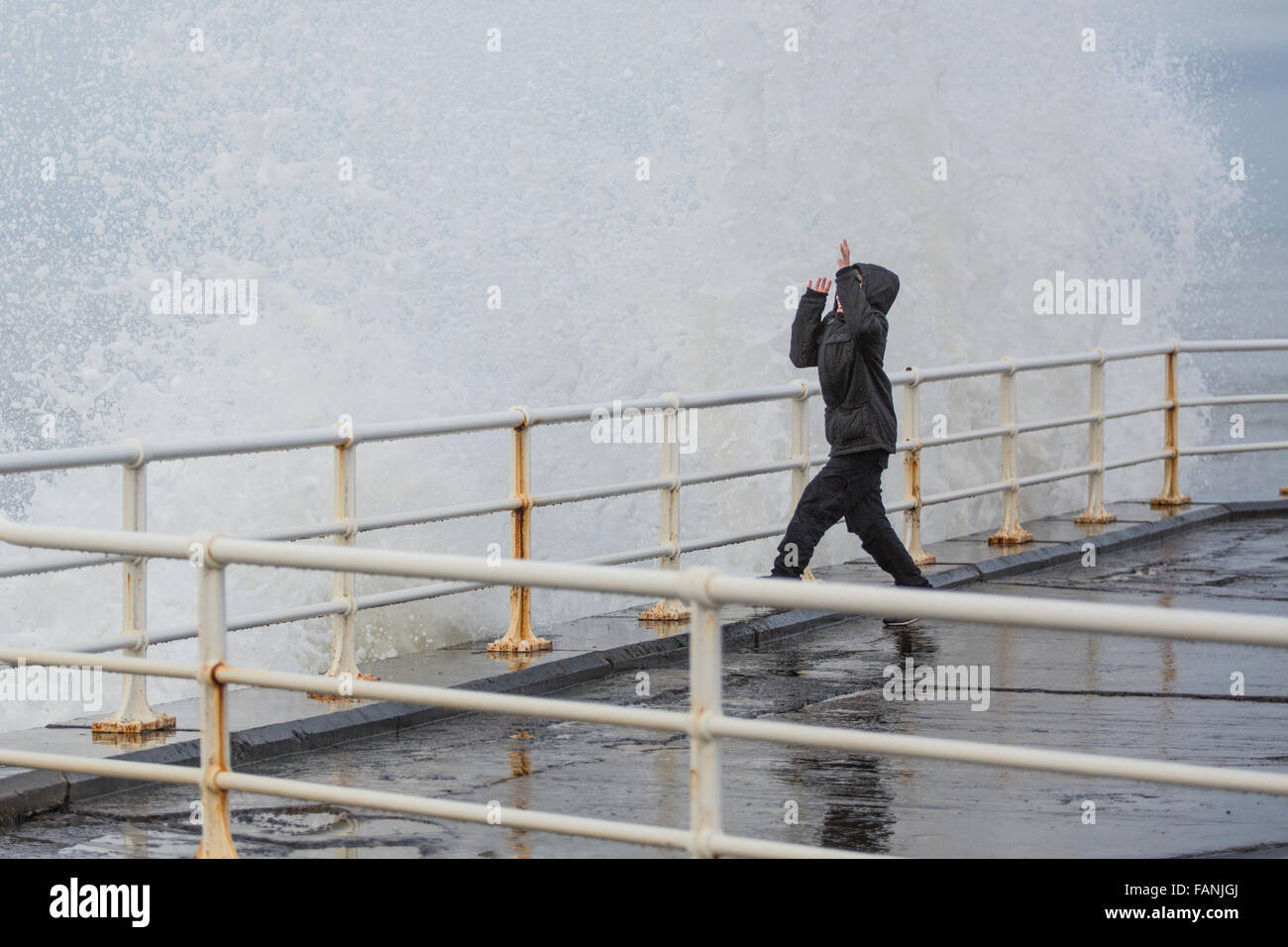 Aberystwyth, Wales, Regno Unito. Il 2 gennaio, 2016. Regno Unito: Meteo nonostante una tregua nei recenti tempeste un notevole rigonfiamento genera drammatica onde si infrangono contro la promenade. Qui un giovane ragazzo è visto schivare le onde. Credito: Alan Hale/Alamy Live News Foto Stock