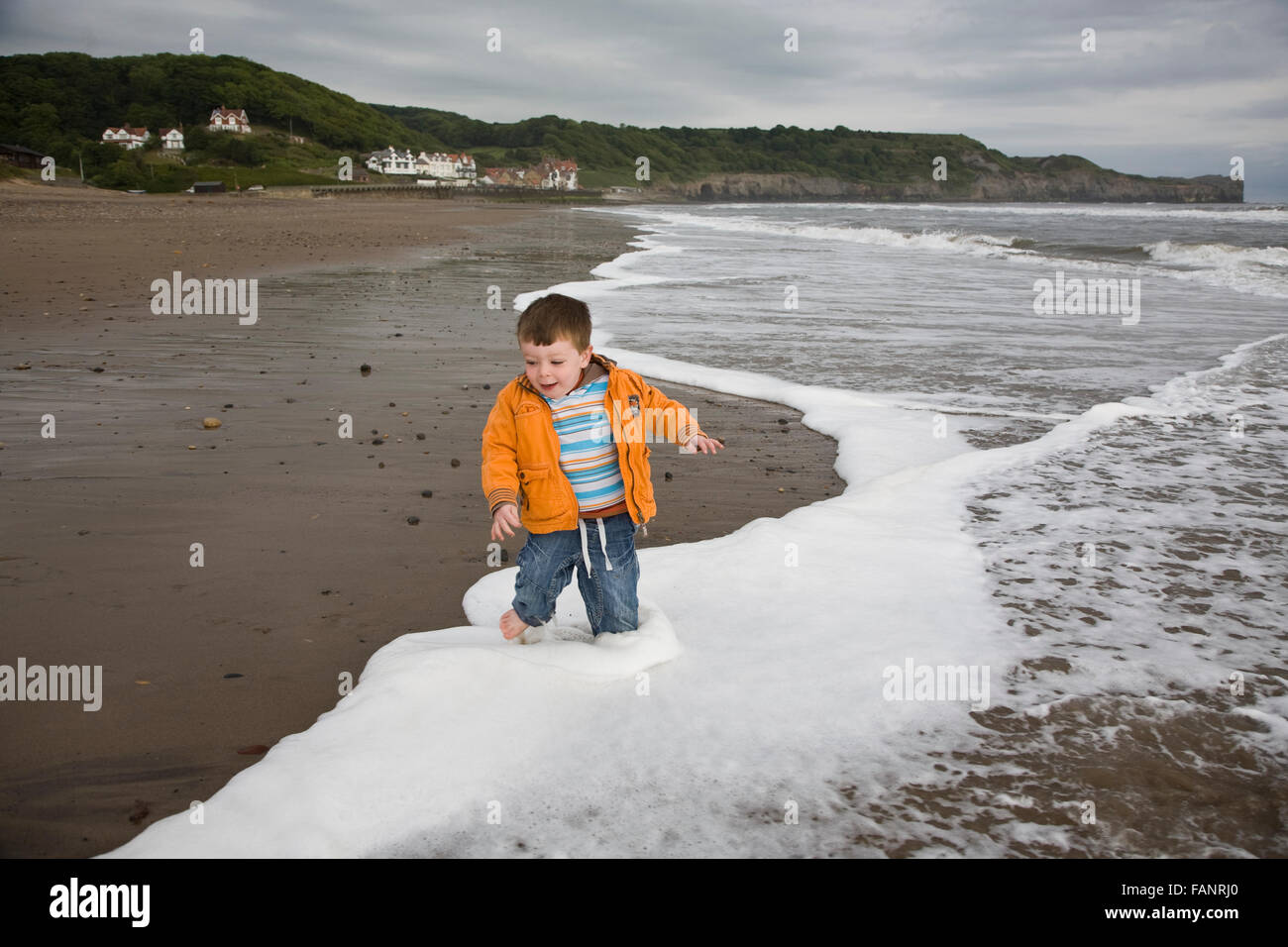 Un giovane ragazzo giocando sulla spiaggia a Saltburn, Yorkshire. Foto Stock