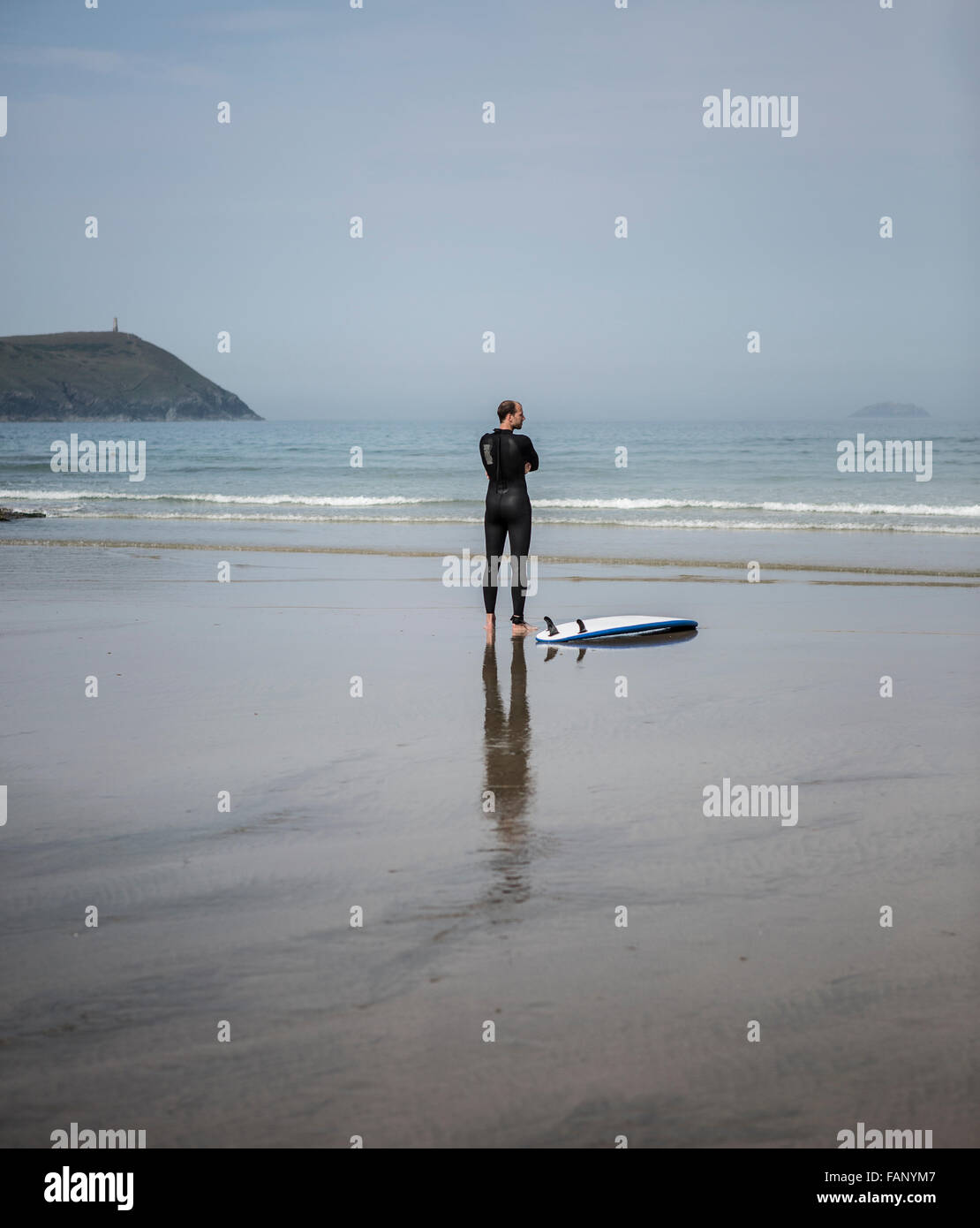 Lone Surfer attende le onde a Polzeath Beach, Cornwall Foto Stock