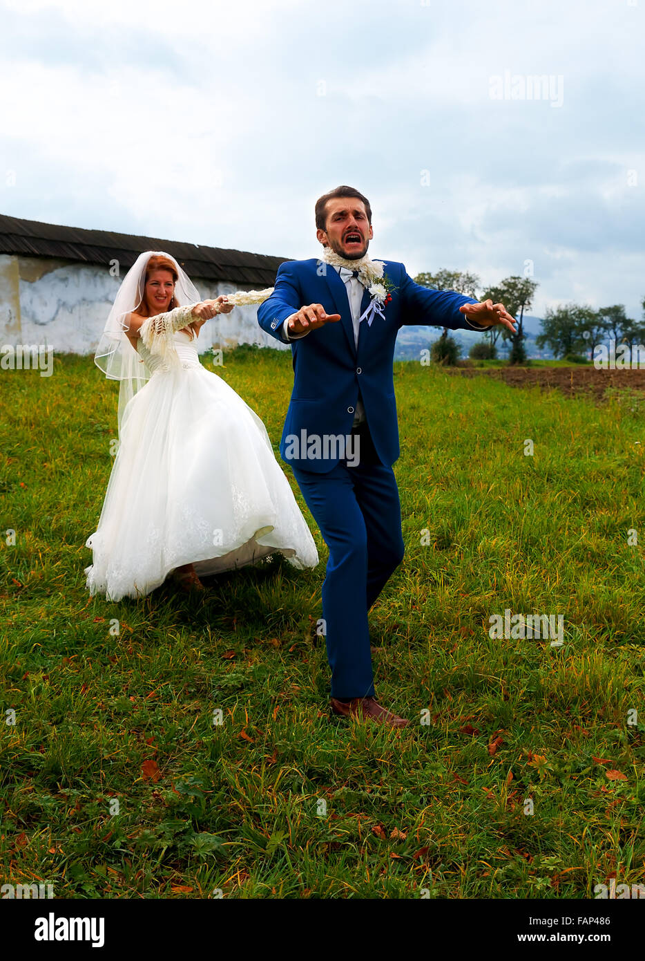Sposa tirando il suo sposo a lei con una corda - strano concetto di  matrimonio Foto stock - Alamy