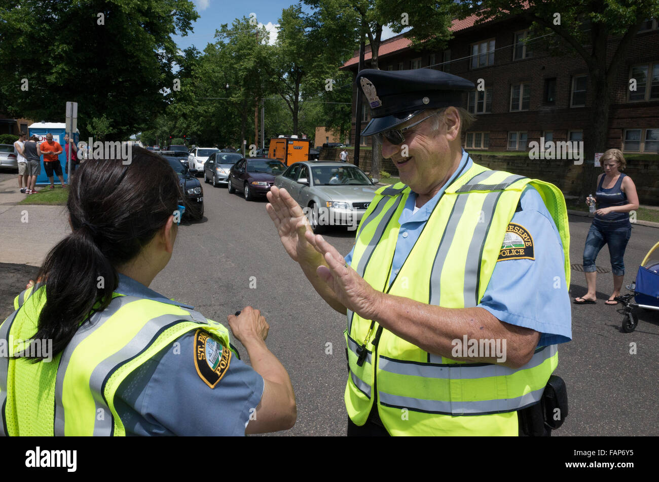 Riserva Senior poliziotto dimostrando segnali a mano a poliziotta asiatica. Grand Old giorno Street Fair. St Paul Minnesota MN USA Foto Stock