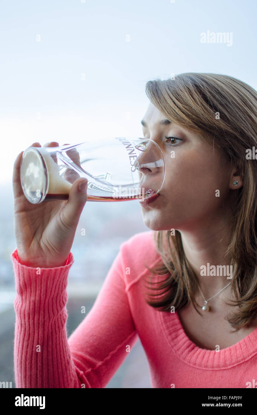 Donna di bere una pinta di Guinness Foto Stock