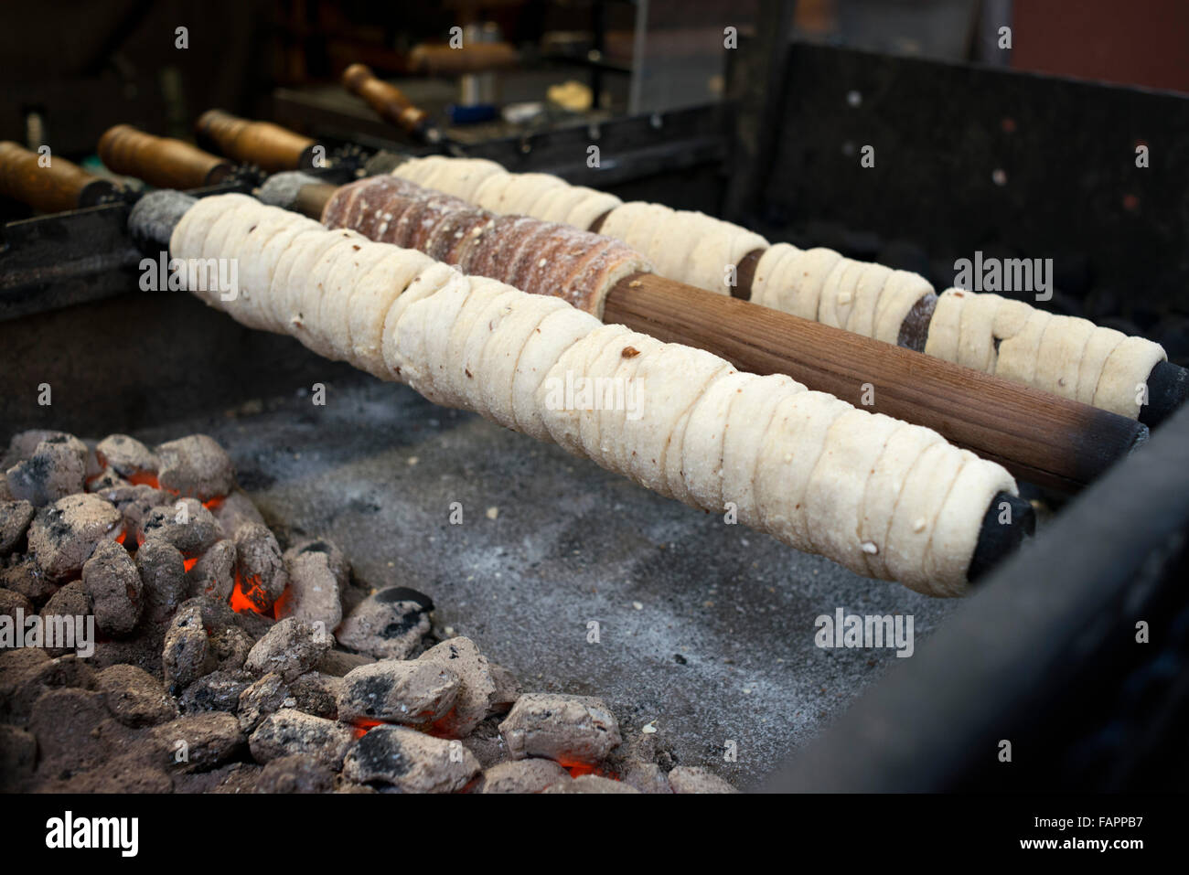Trdelník bancarelle. Il Trdelnik è una massa di farina, zucchero, uova, lievito, la cannella e il latte che è teso e avvolto su un di legno Foto Stock
