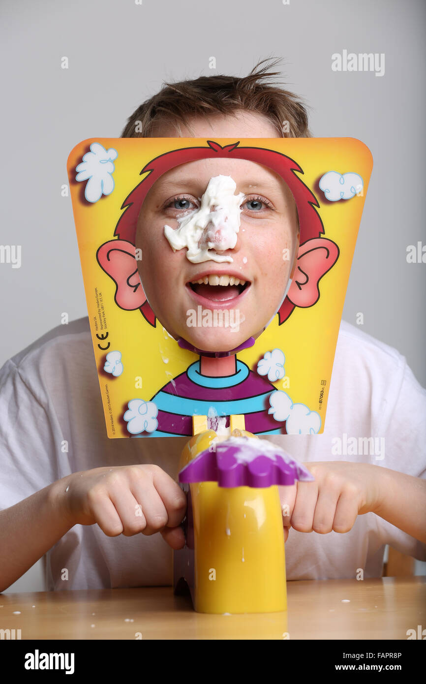 Un ragazzo giocando il gioco di bordo faccia a torta da Hasbro getting ricoperto di crema di latte Foto Stock