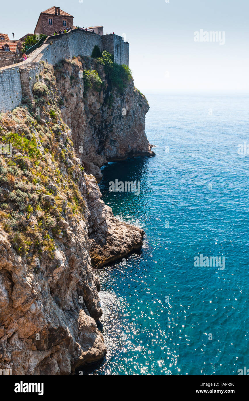 Le scoscese scogliere, al di sotto del sentiero cinto di mura intorno a Dubrovnik rientrano nelle limpide acque del Mare Adriatico, Croazia, Europa Foto Stock