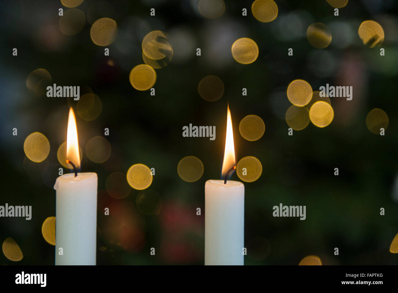 Due candele con albero di Natale luci in background Foto Stock