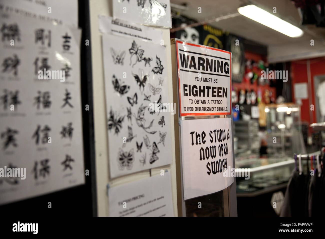 Interno di un tatuaggio piercing / salone, dotato di segno di età e di diversi disegni. Foto Stock