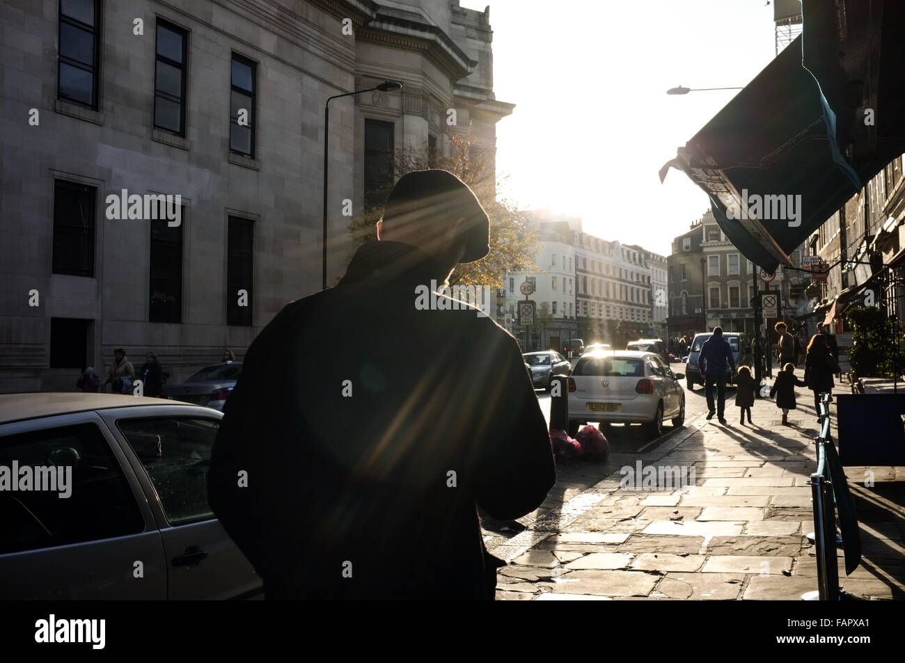 La luce del sole di colpire street nel centro di Londra con uomo nel tappo piatto in primo piano. Foto Stock