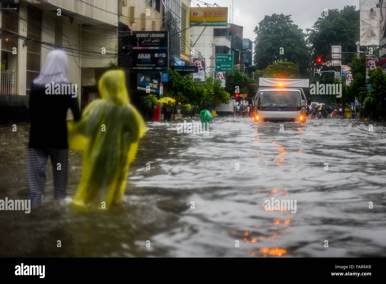 I bambini camminano attraverso l'acqua in una strada allagata durante una pioggia pesante nel centro di Jakarta, Indonesia. Foto Stock