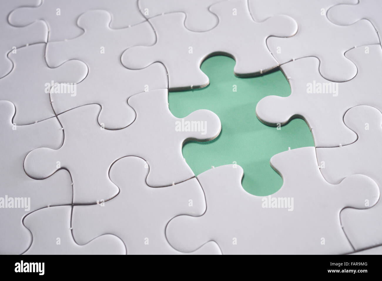Puzzle con pezzo mancante isolato su sfondo verde. Foto Stock