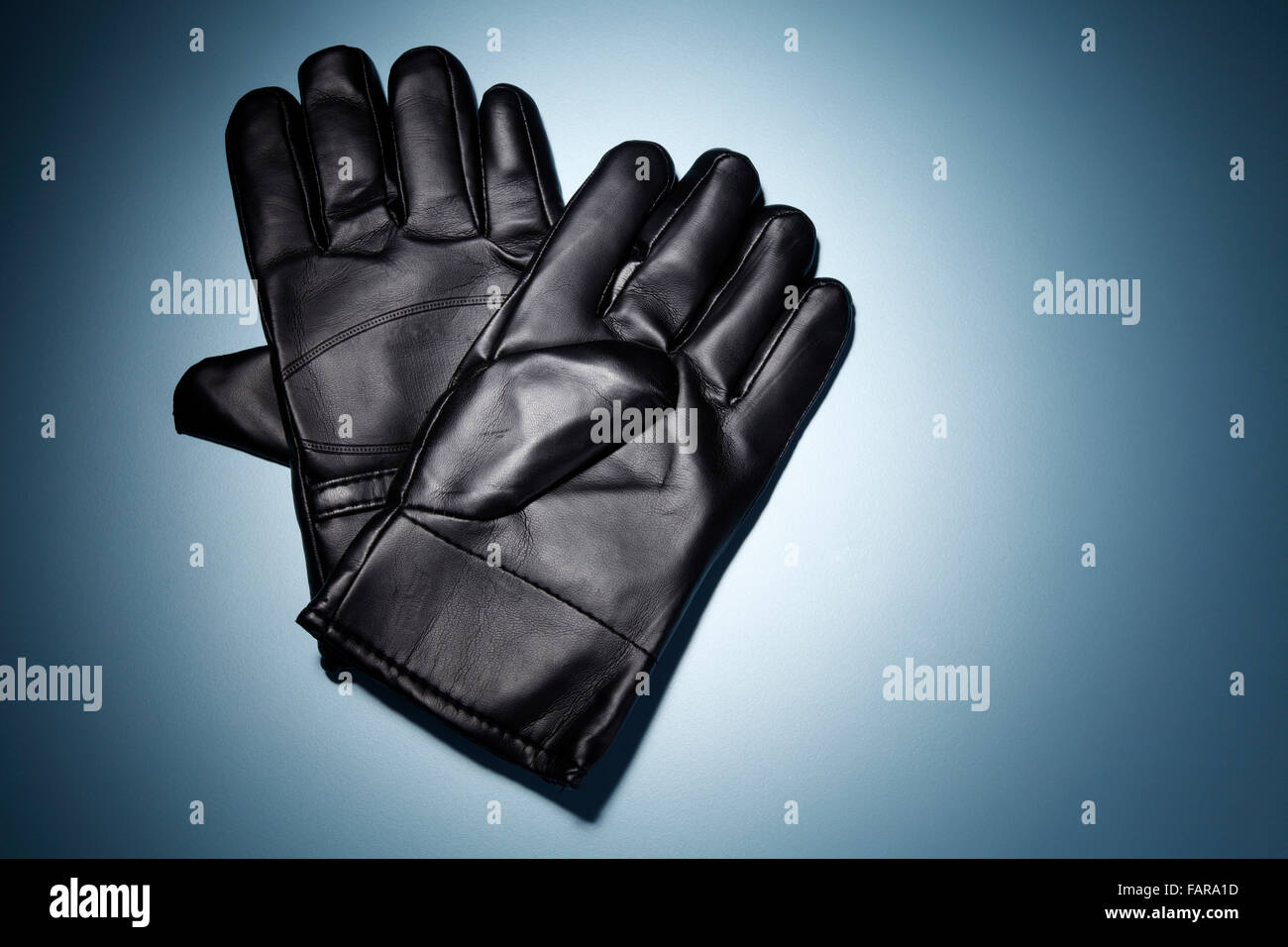Un paio di guanti neri isolati su sfondo blu. Foto Stock