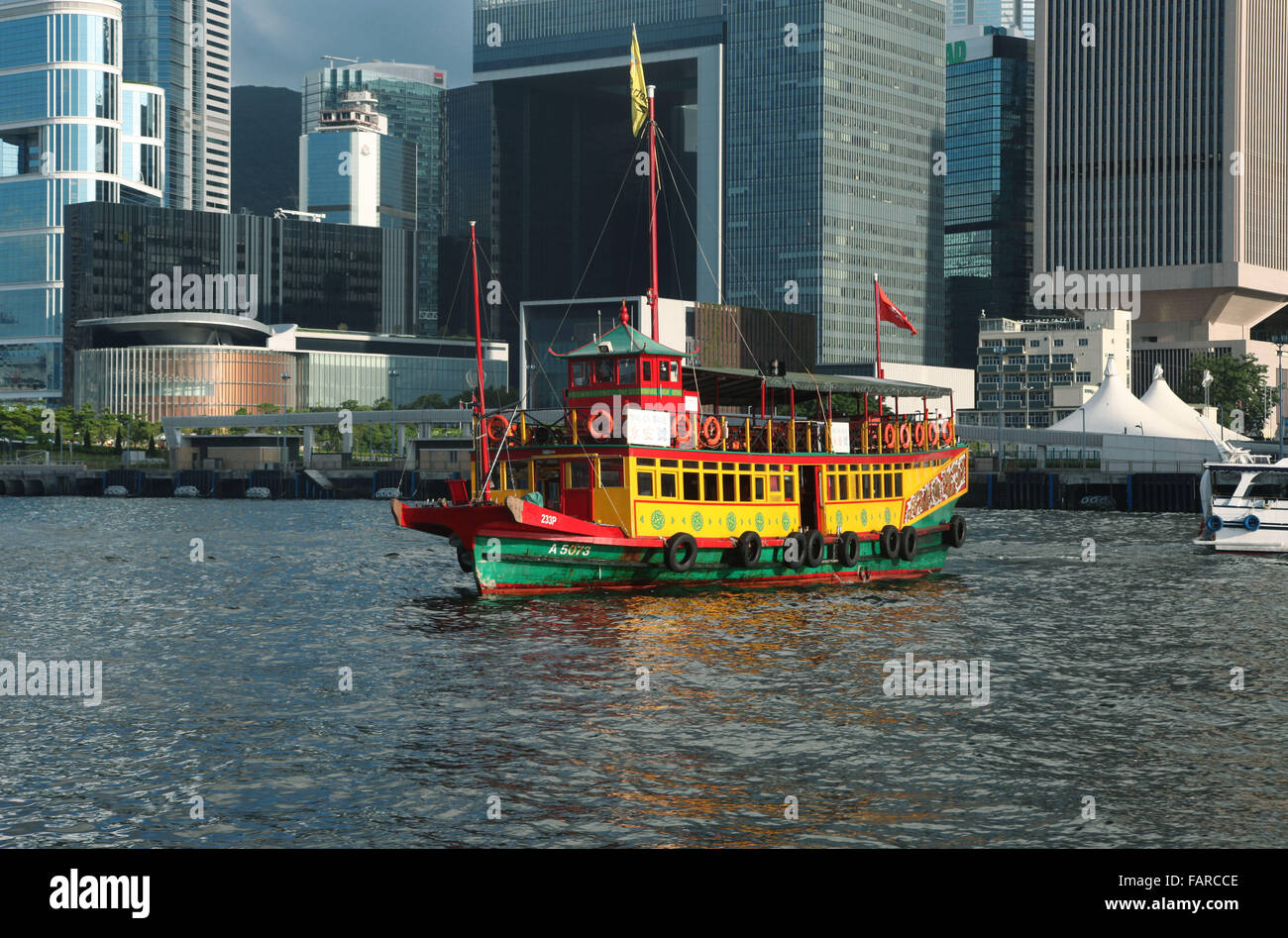 Si tratta di una foto di una barca colorata in Hong Kong Victoria Bay. Possiamo vedere il quartiere finanziario in background Foto Stock
