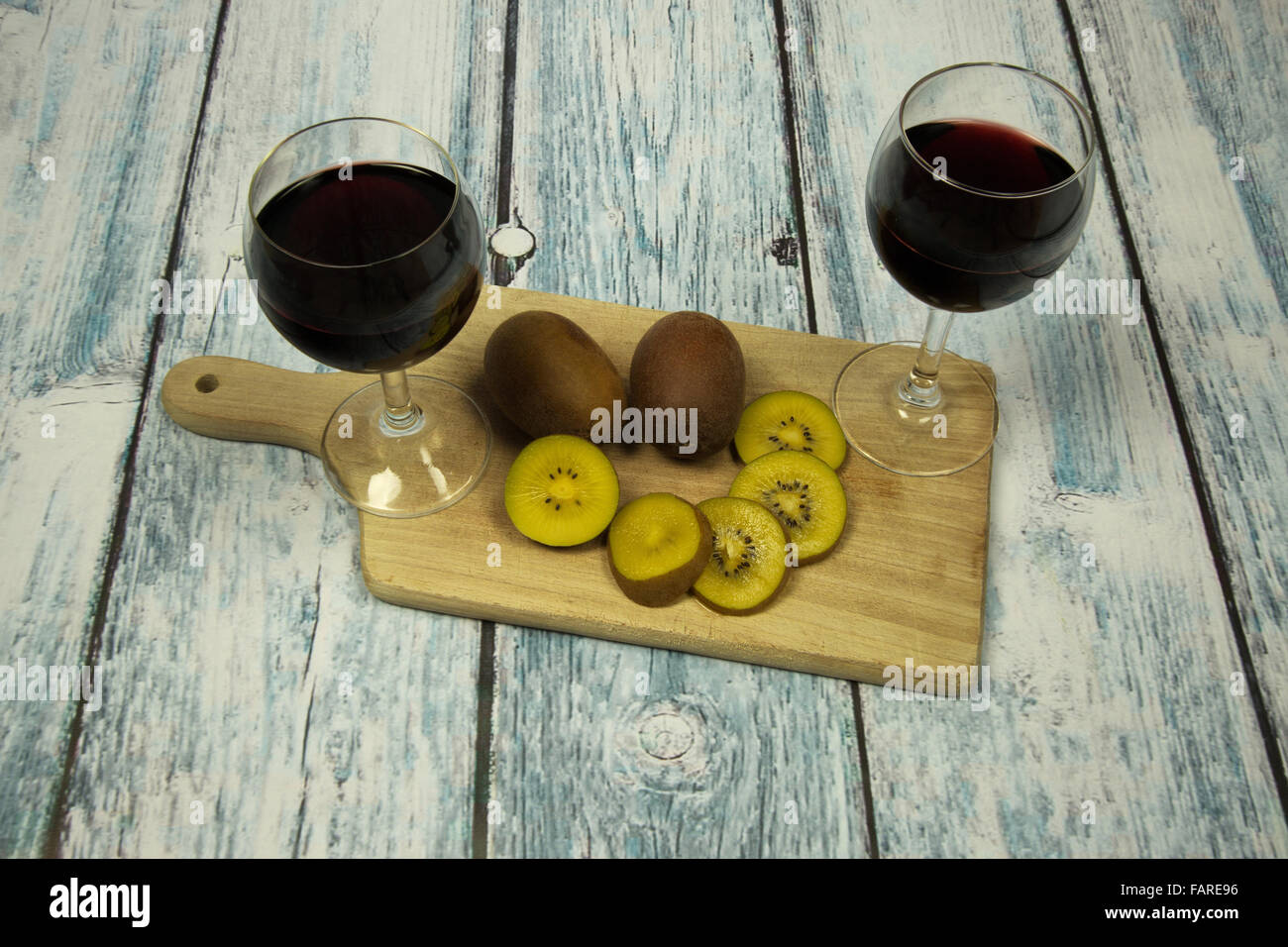 Due bicchieri di vino rosso e kiwi su di un piano in legno, vintage.vista orizzontale. Foto Stock