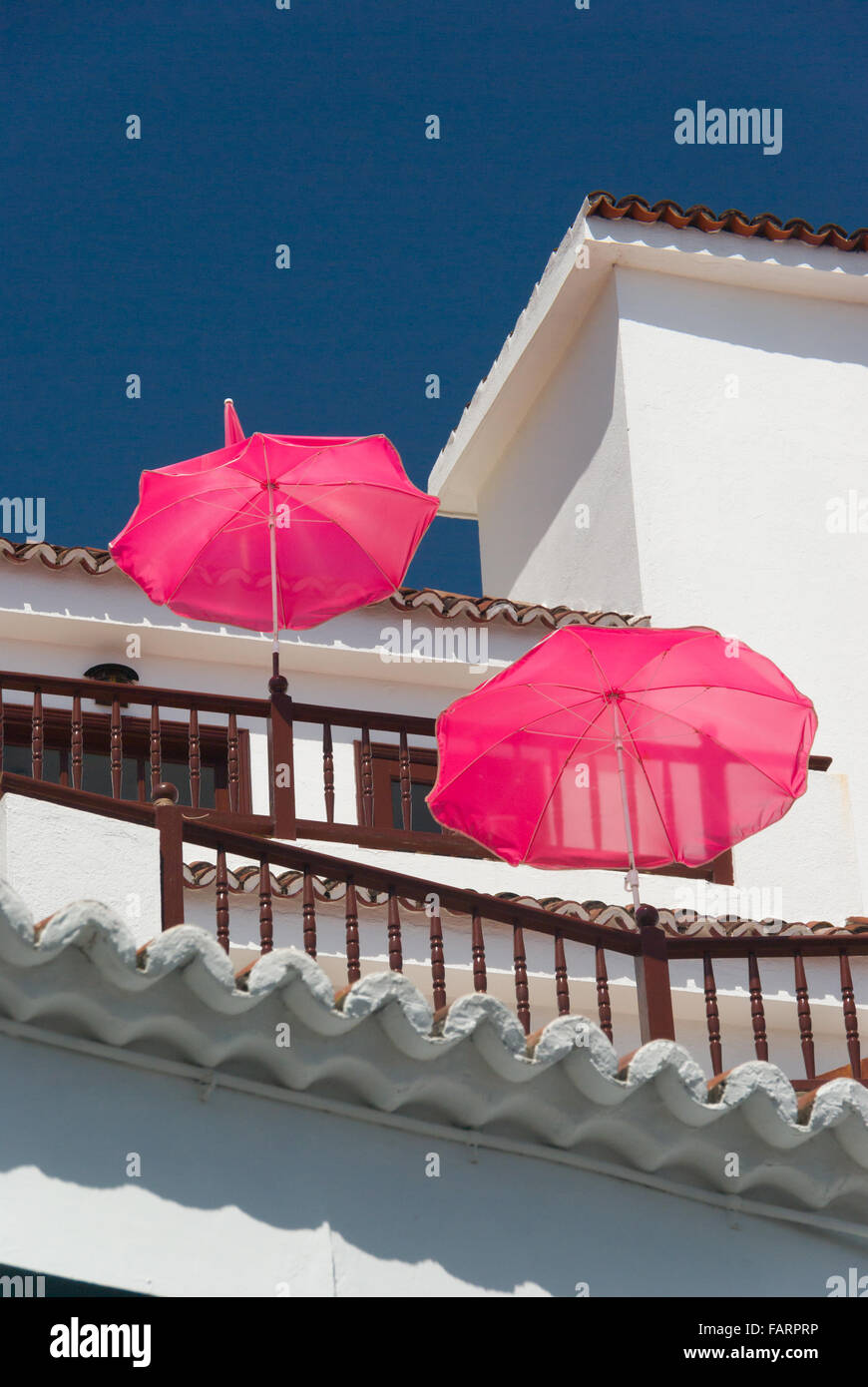 Balcone bianco casa rosa con ombrelloni su uno sfondo di cielo blu a La Palma Isole Canarie Spagna Foto Stock